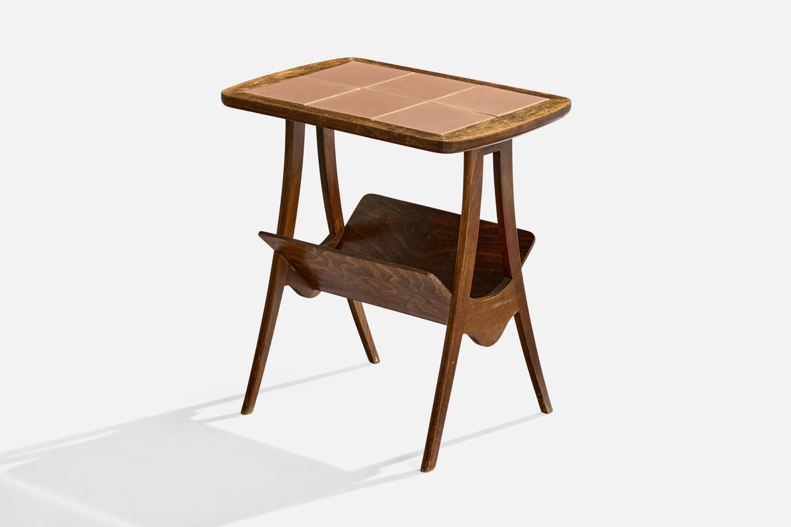 A dark-stained oak and ceramic tile side table with magazine holder designed and produced in France, c. 1950s.

The tile tabletop presents with light staining. 

Minor wear to wooden legs consistent with age and use.

Overall Dimensions (inches):