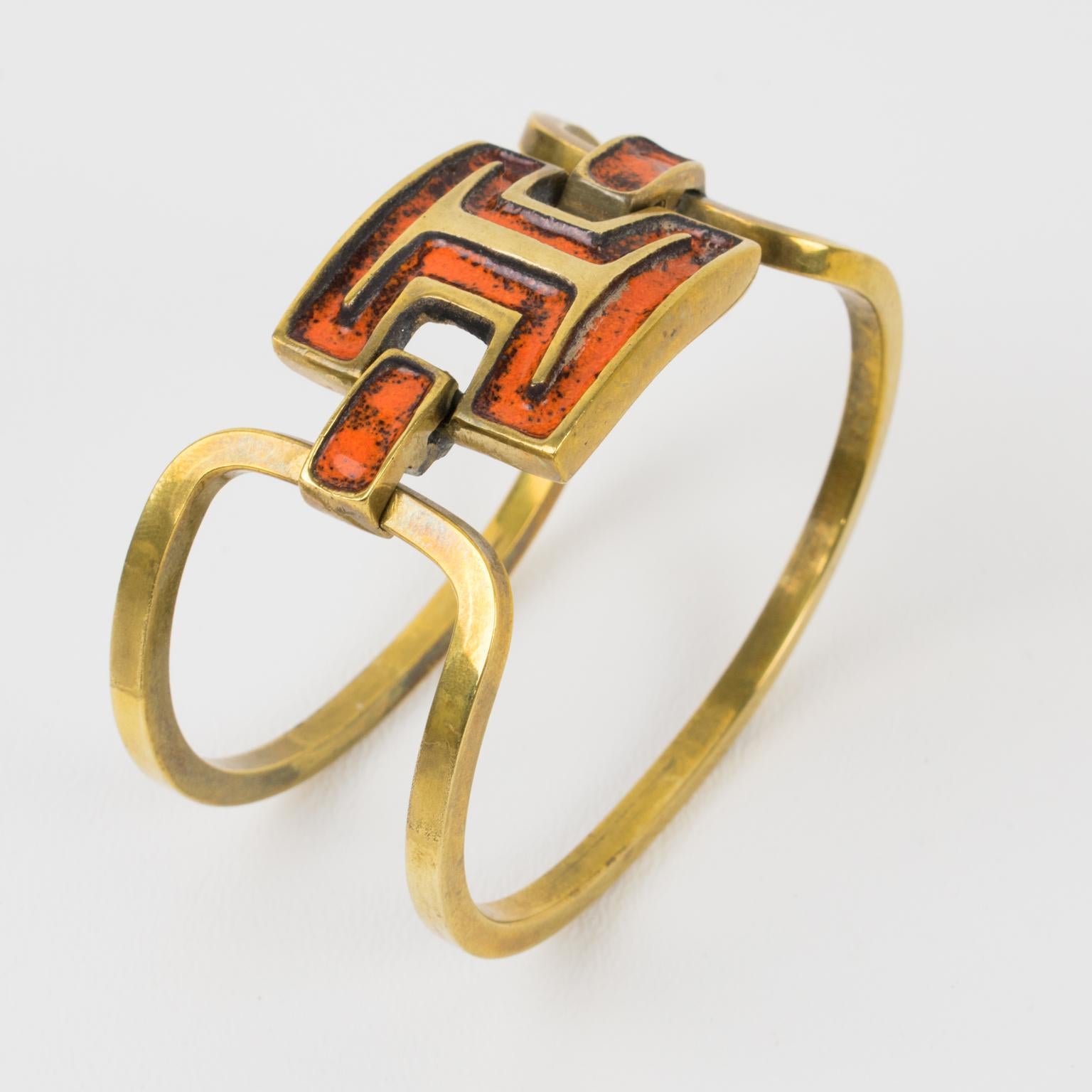 French designer St Luc designed this lovely modernist bronze and enamel clamper bracelet in the 1960s. The piece boasts a gilded bronze two-band design with geometric gilded bronze metal carved elements topped with orange and black enamel. The