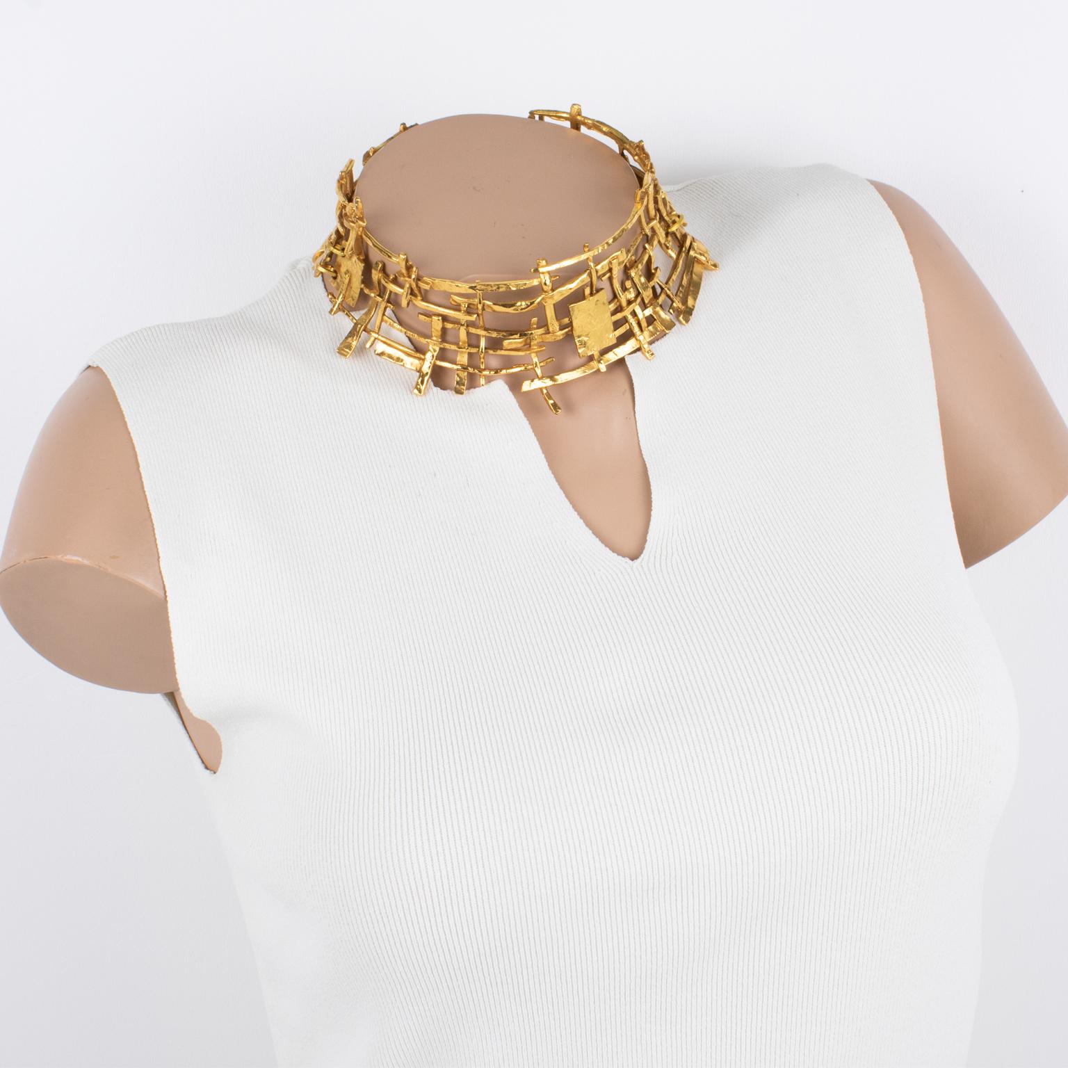 This spectacular around-the-neck necklace was designed in the 1990s by a French designer studio. The massive torque shape features a brutalist futuristic carved and see-thru design built with fine gilded metal. The piece is articulated in three
