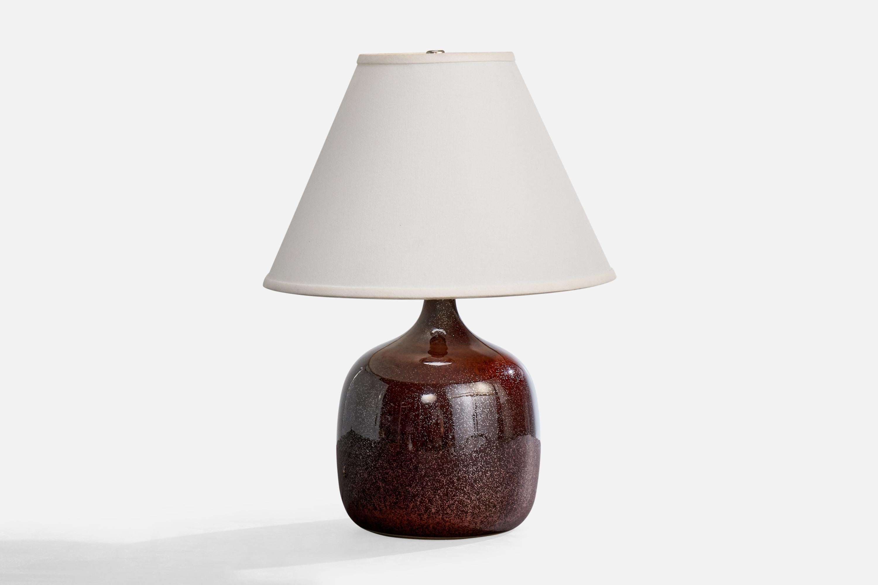 A red-glazed ceramic table lamp designed and produced in France, c. 1950s.

Wear consistent with age and use

Dimensions of Shade (inches): 5.25” Top Diameter x 12.5” Bottom Diameter x 7.75” Height

Overall Dimensions (inches): 10.5