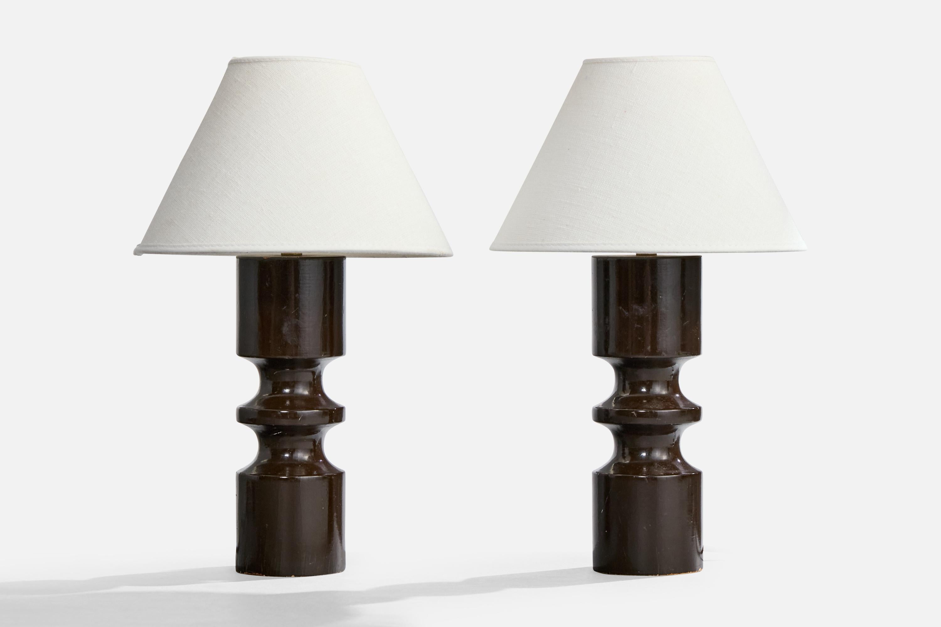 A pair of dark brown-lacquered wood and brass table lamps designed and produced in France, c. 1950s. 

Scratching and losses present throughout both lamps, predominantly near bottom.

Dimensions of Lamp (inches): 9.5“ H x 2.875” Diameter

Dimensions