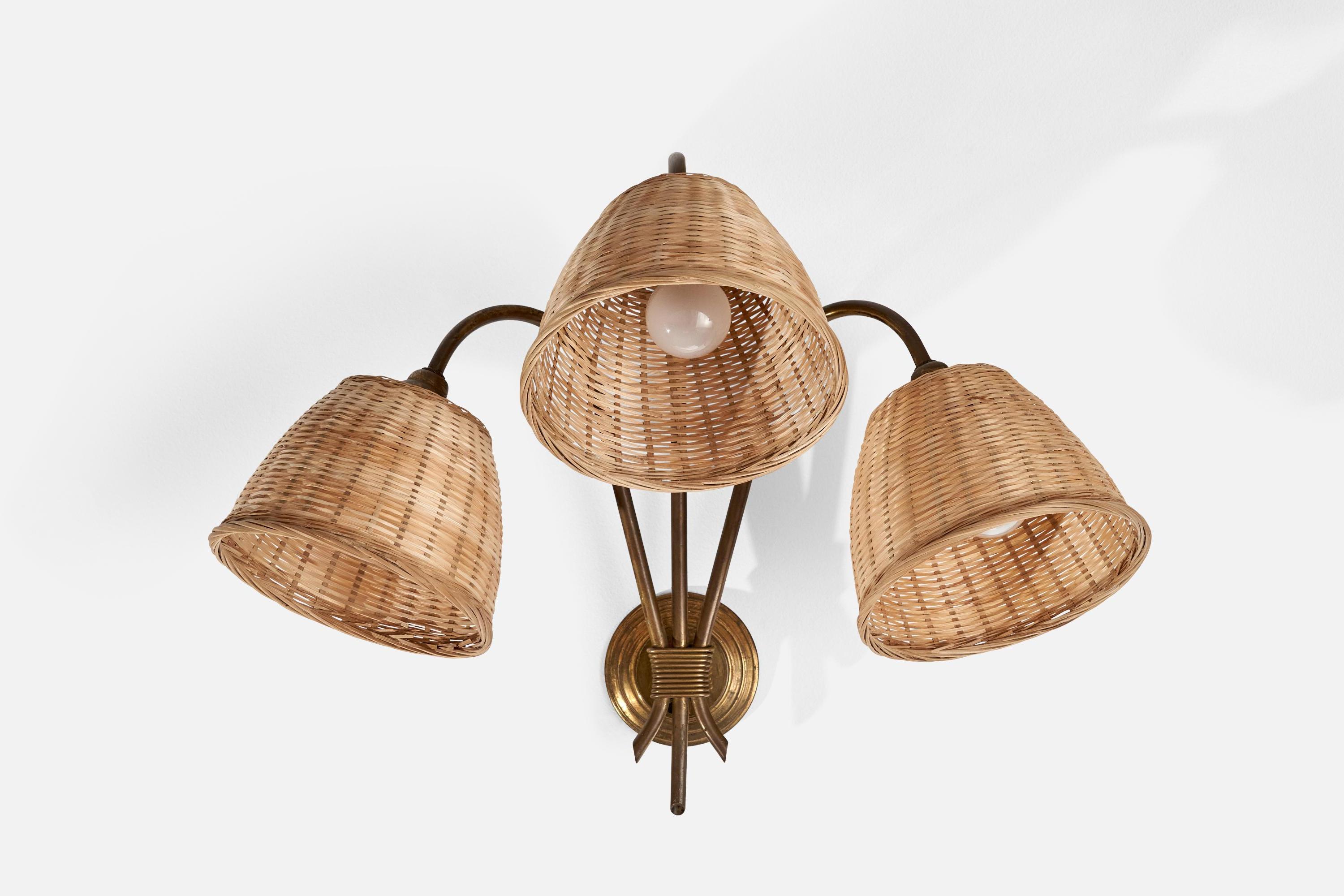 A three-armed brass and rattan wall light designed and produced in France, 1940s.

Overall Dimensions (inches): 16” H x 21” W x 17.75” D
Back Plate Dimensions (inches): 3.75” H x.50” D
Bulb Specifications: E-12 Bulb
Number of Sockets: 3
All lighting