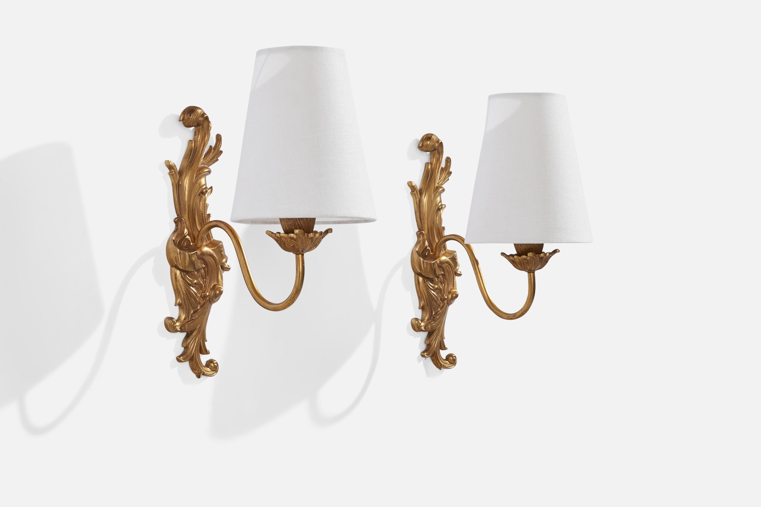 A pair of brass and white fabric wall lights designed and produced in France, c. 1940s.

Overall Dimensions (inches): 10” H x 3”  W x 6.25”  D
Back Plate Dimensions (inches): N/A
Bulb Specifications: E-12 Bulb
Number of Sockets: 2
All lighting will