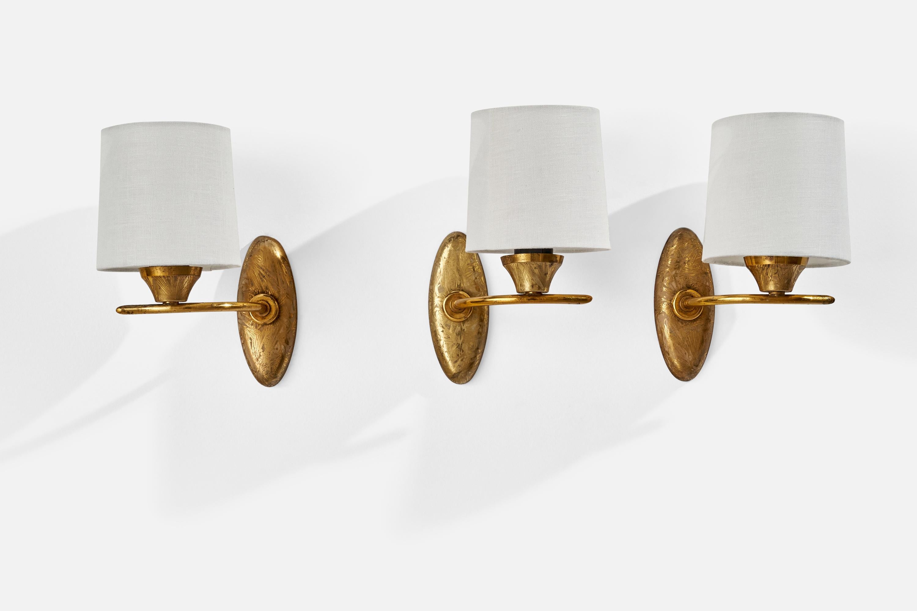 A set of 3 impressed brass and white fabric wall lights designed and produced in France, c. 1950s.

Overall Dimensions (inches): 8.75” H x 4.57” W x 5.43” D
Back Plate Dimensions (inches): 5.12” H x 1.96” W x 0.50” D
Bulb Specifications: E-12