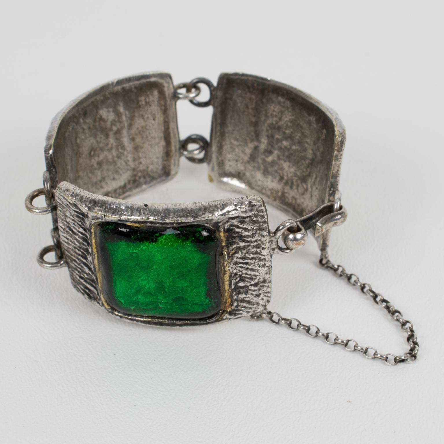 French artist Willy designed this elegant Mid-Century link bracelet in the 1950s. The piece features geometric silvered bronze hand-made shaped elements topped with thick poured glass cabochons in emerald green color with a glittering textured