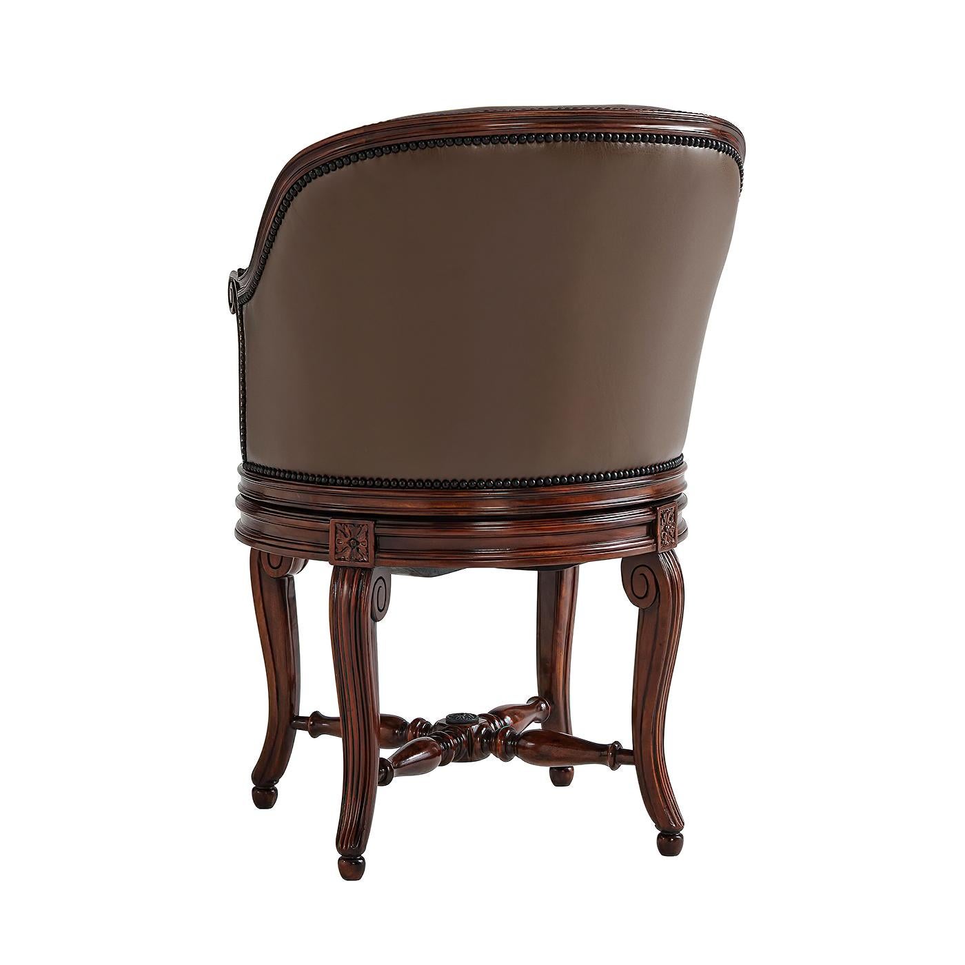 A French Louis XVI style leather upholstered walnut desk armchair, with a circular swivel action, upholstered seat, carved scroll arms and legs and an 'x' stretcher. The leather upholstery with antiqued brass nailhead trim.

Dimensions: 22