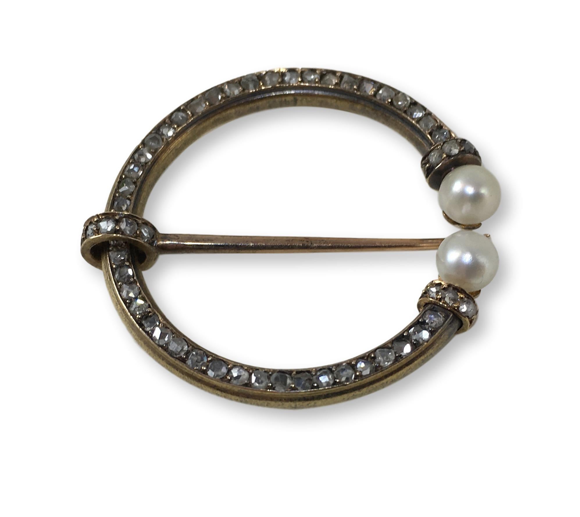 A beautifully made fibula brooch set to the hoop with rose-cut diamonds, terminating in a pair of button-shaped pearls. The gems are mounted in 18 carat gold.

The brooch contains 54 diamonds with a total estimated weight of 1.62 carats and 2
