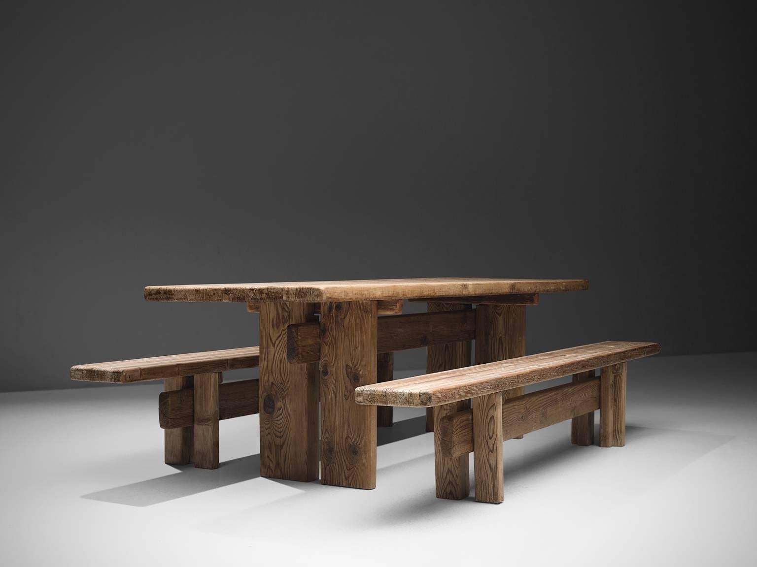 Dining set in pine wood, France, circa 1950. 

These pine wooden benches are robust and architectural in their design. The bulky benches and matching table are made of beautiful pine wood which developed a nice, rustic patina through age and use.