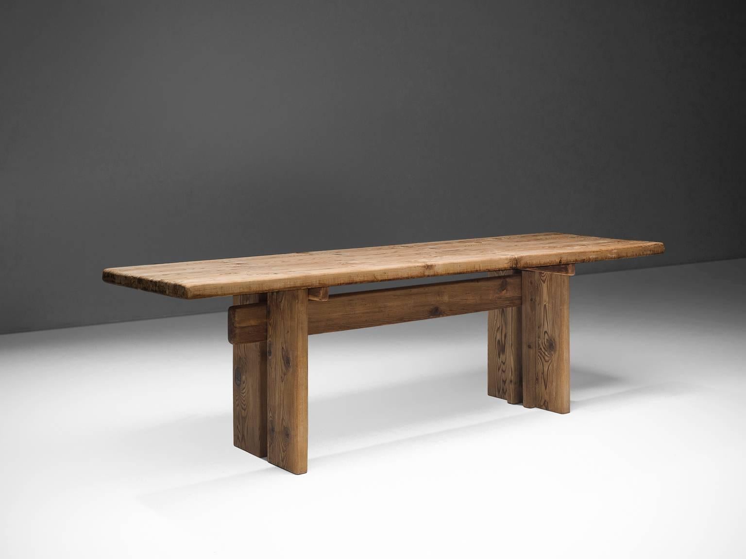 Dining table in pine wood, France, circa 1950. 

This pine table is robust and architectural in its design. The bulky piece is made of beautiful pine wood which developed a nice, rustic patina through age and use. The traditional wooden