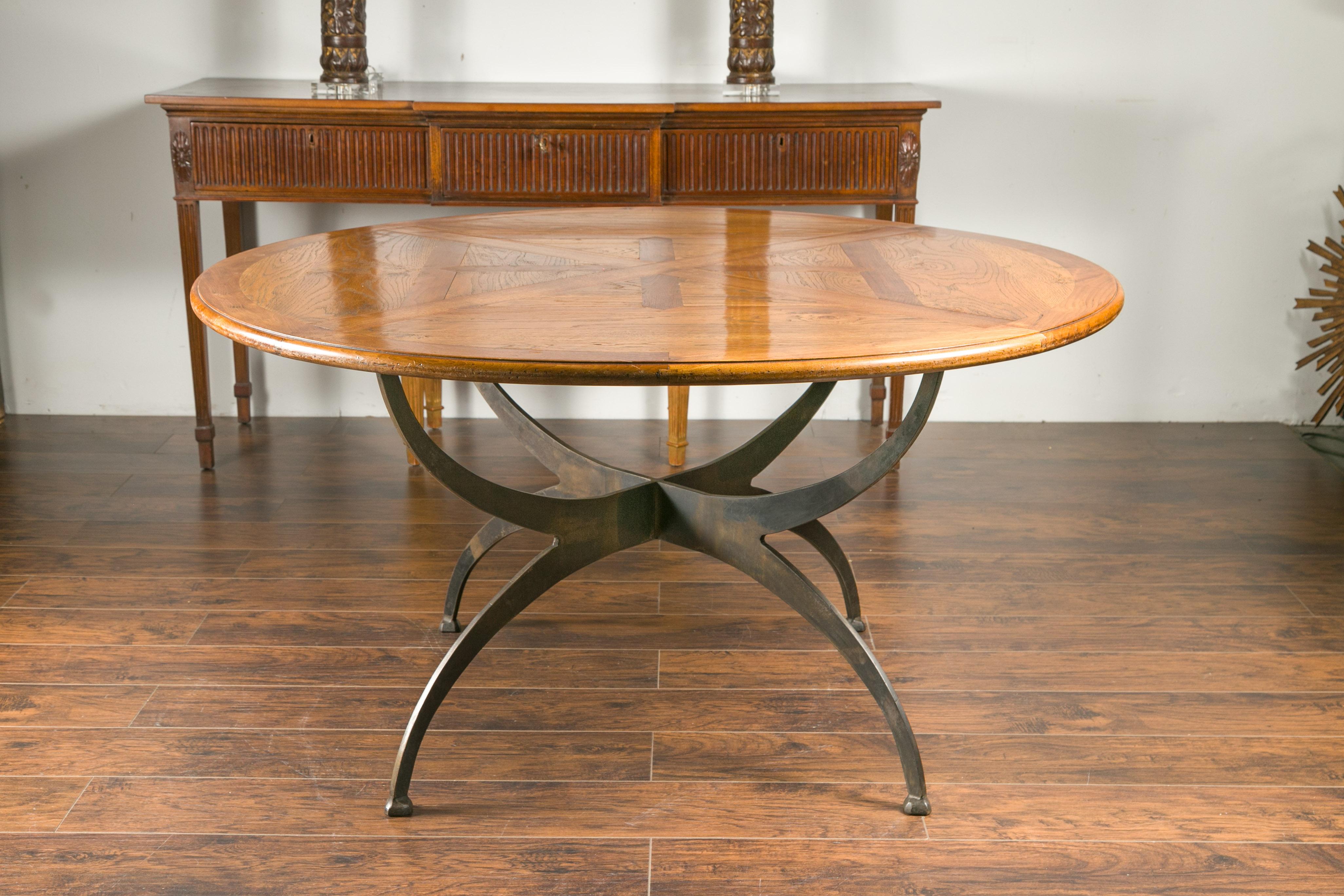 A French dining table with round parquetry top from the early 20th century and new custom iron base. Capturing our attention with its circular parquetry top dating from the early 1900s, this dining table is raised on a new custom iron base made of