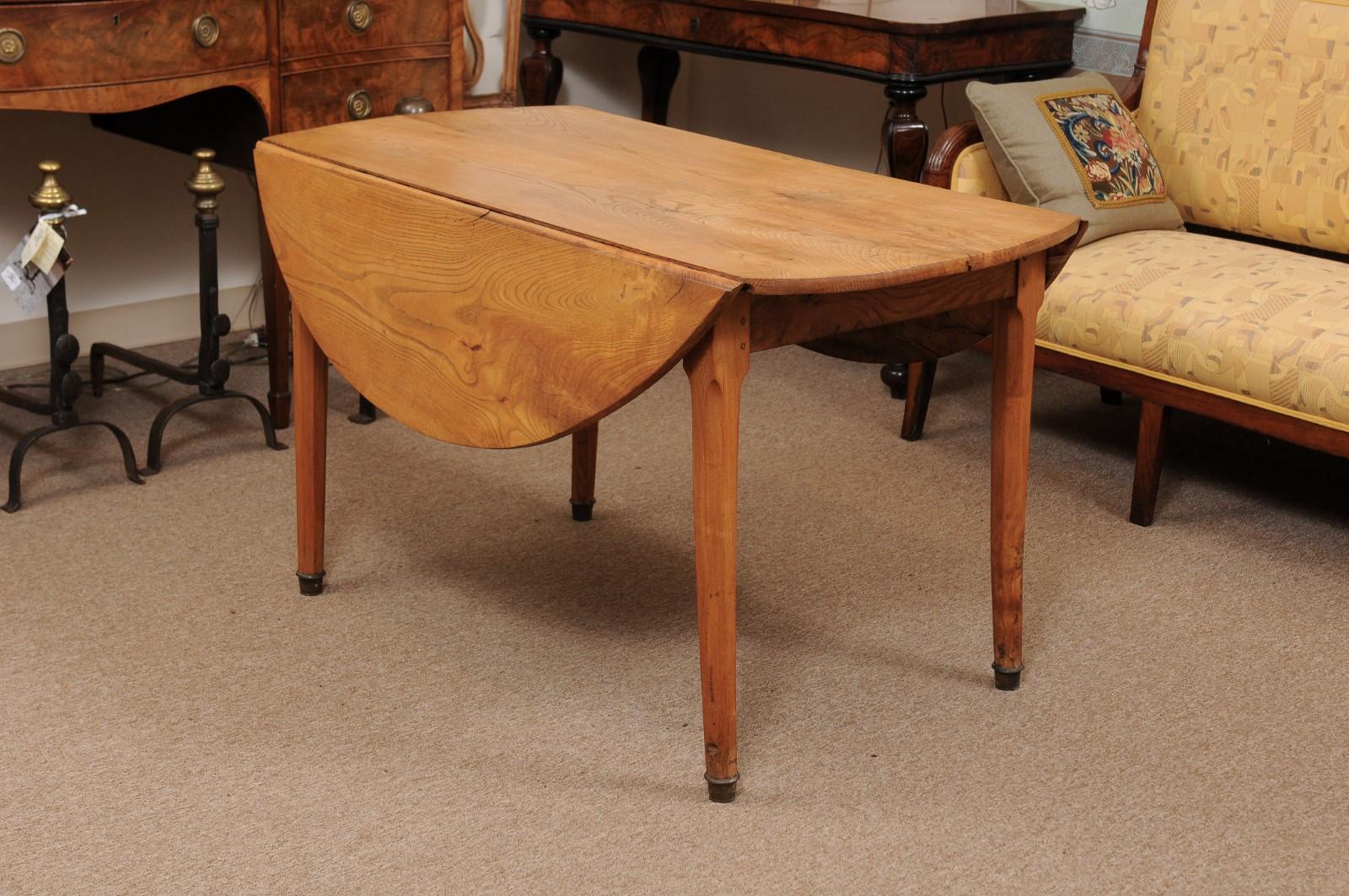 A turn of the 19th century French Directoire ashwood oval drop-leaf table with tapered legs ending on brass capped feet. 

 