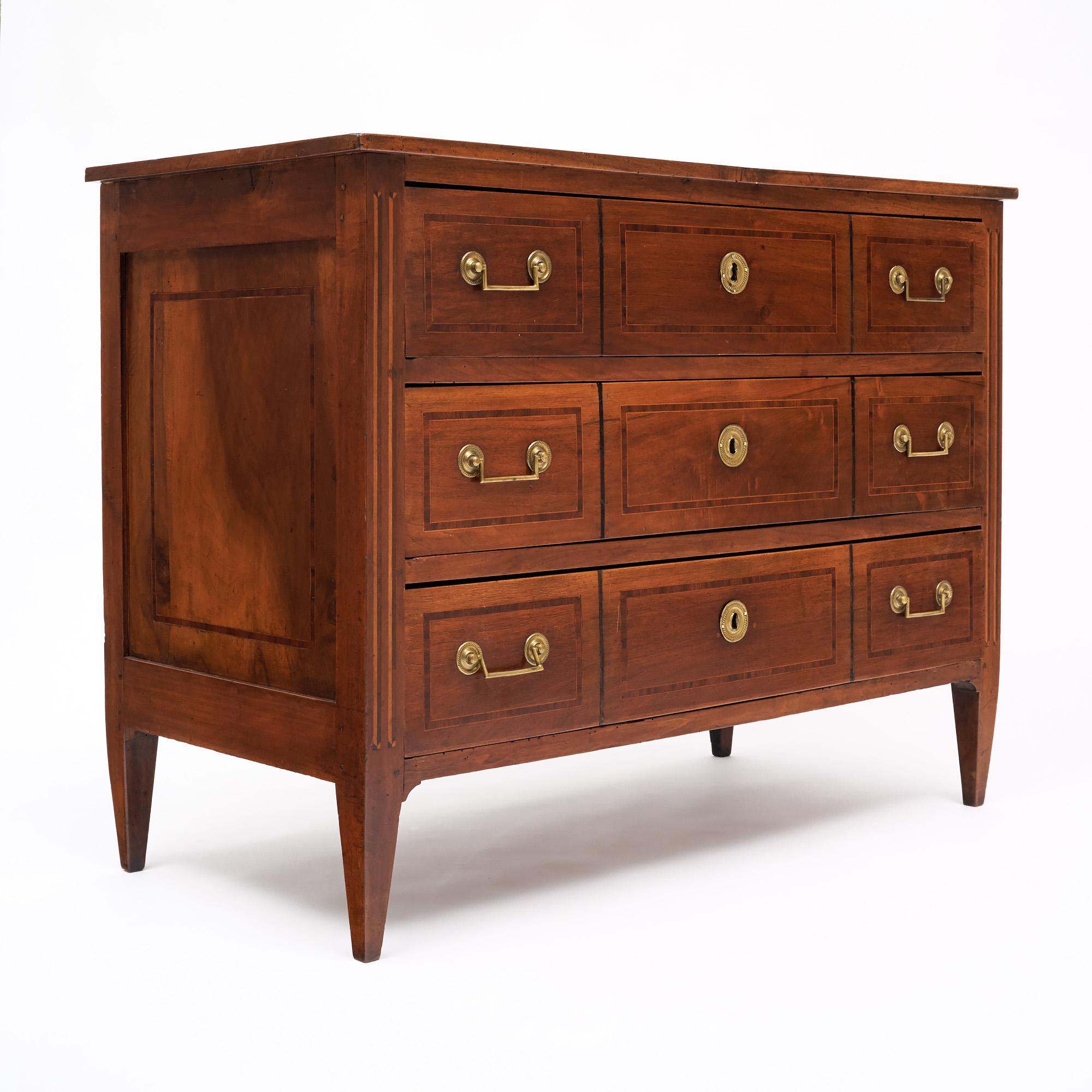 Chest of drawers from France from the Directoire period. The piece is made of solid cherry wood construction and features a beautiful rosewood and tinted rosewood inlay adorning each drawer. There are three dovetailed drawers, all with gilt bronze