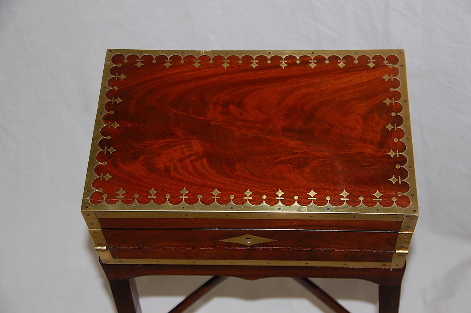 French Directoire period double opening mahogany writing box now on bespoke mahogany stand. This small elegant writing box is edged in brass, the lid having an elaborate scalloped edge punctuated by brass stars, balls and lines. This box with its