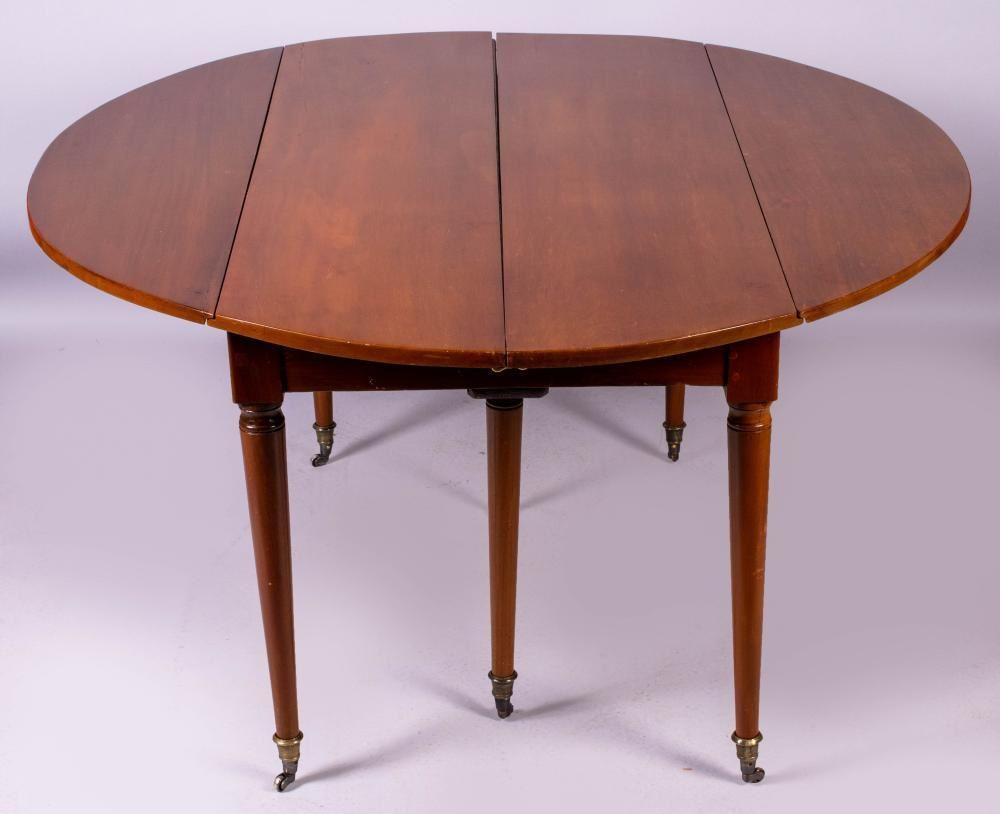 A Directoire period drop-leaf dining table in walnut with 6 tapered legs capped with brass casters, and 2 removable leaves (18