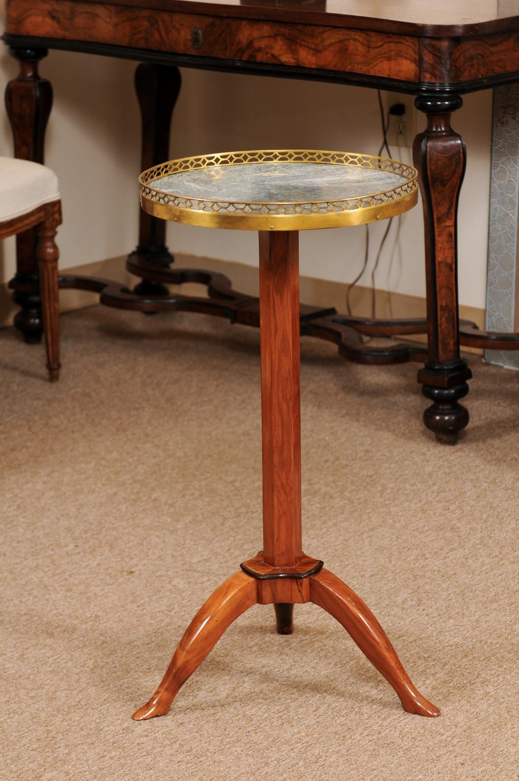 The French Directoire French candle stand featuring round green marble top with brass gallery, pedestal base and tripod legs.

 