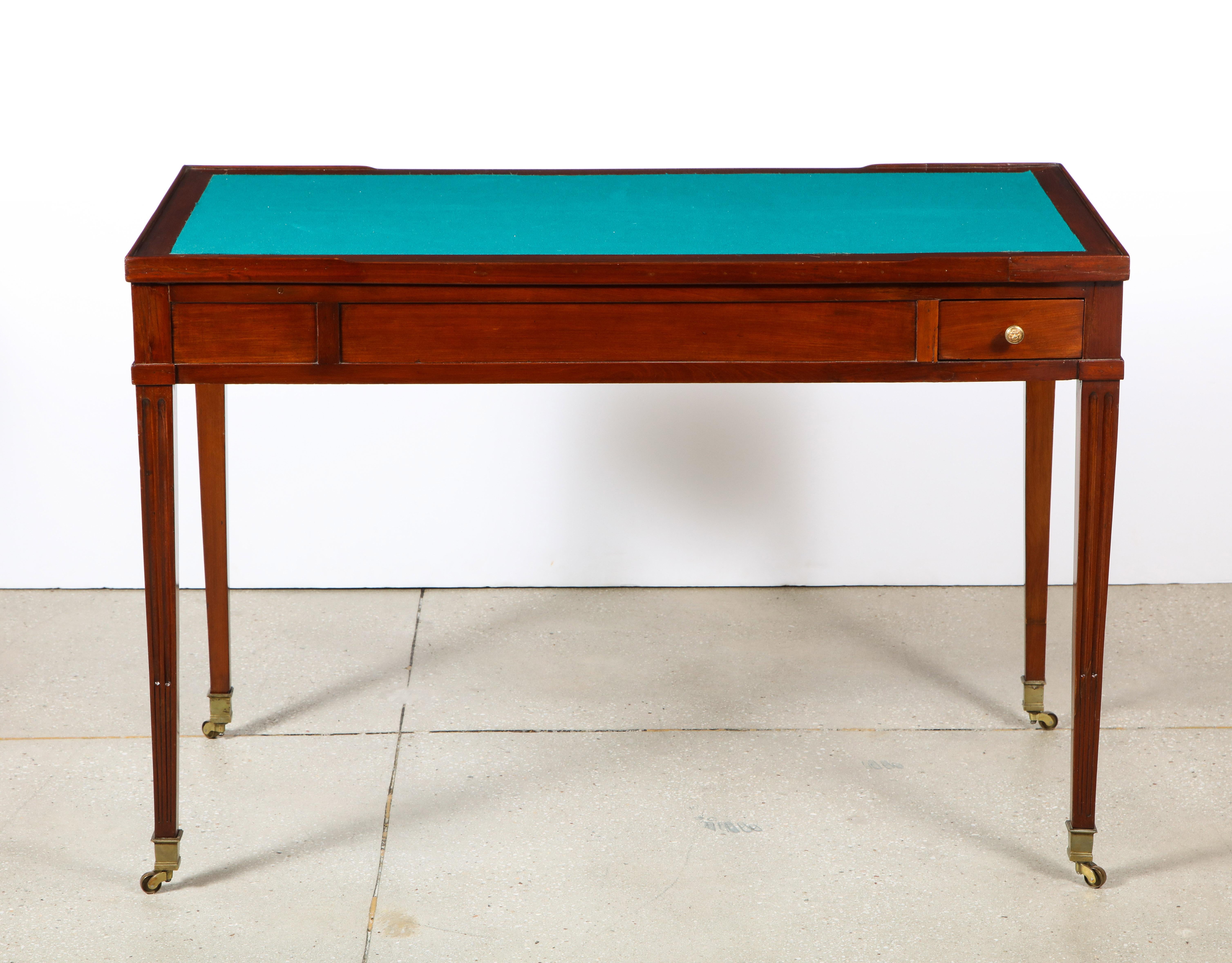 The dual side felt inset top, removes to reveal ebony interior inlaid with stained fruitwood to create backgammon board. 2 exterior drawers and all on tapered legs with brass castors.
    