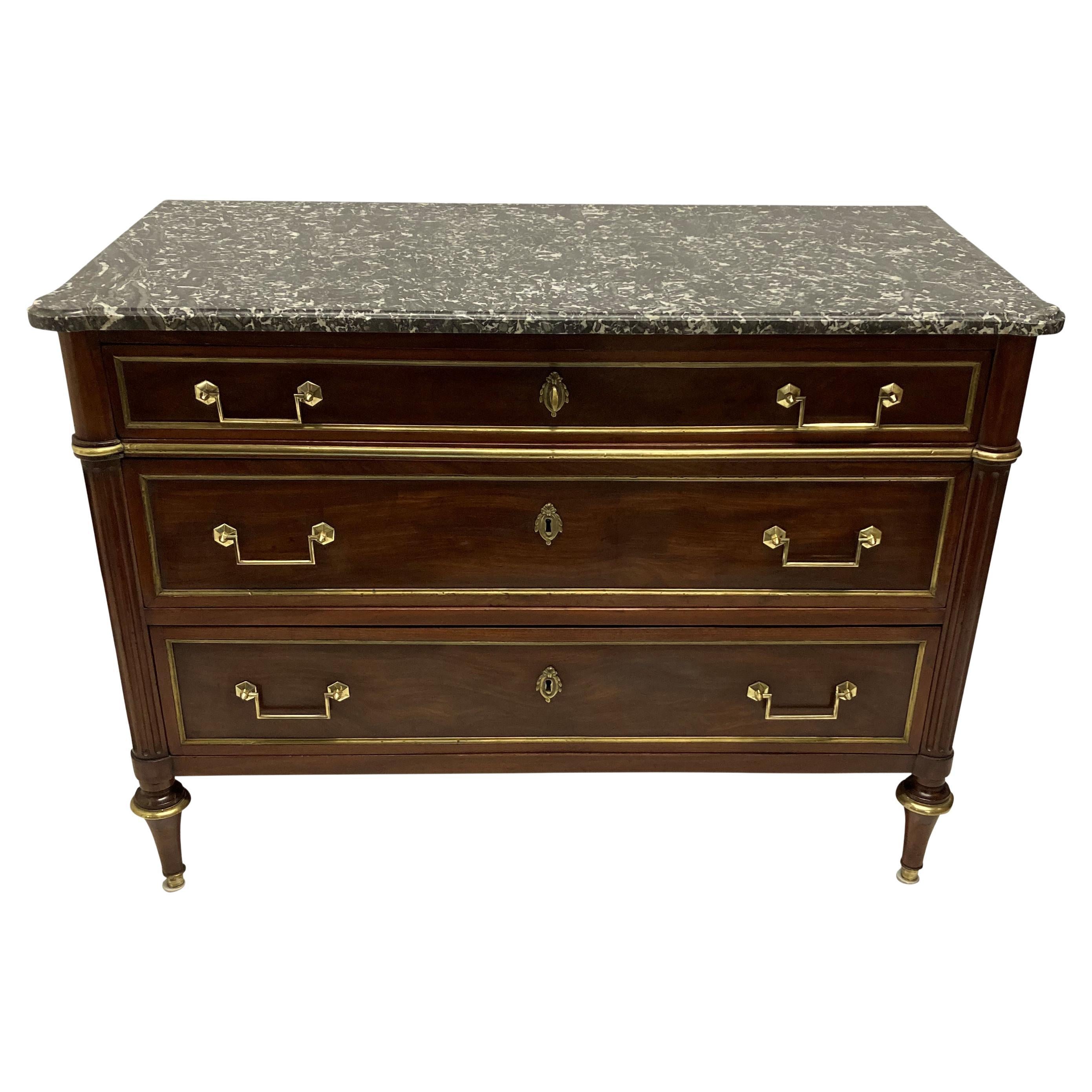 A French mahogany, three drawer Directoire commode, with brass mounts and inlay and a shaped variegated pale grey marble top.