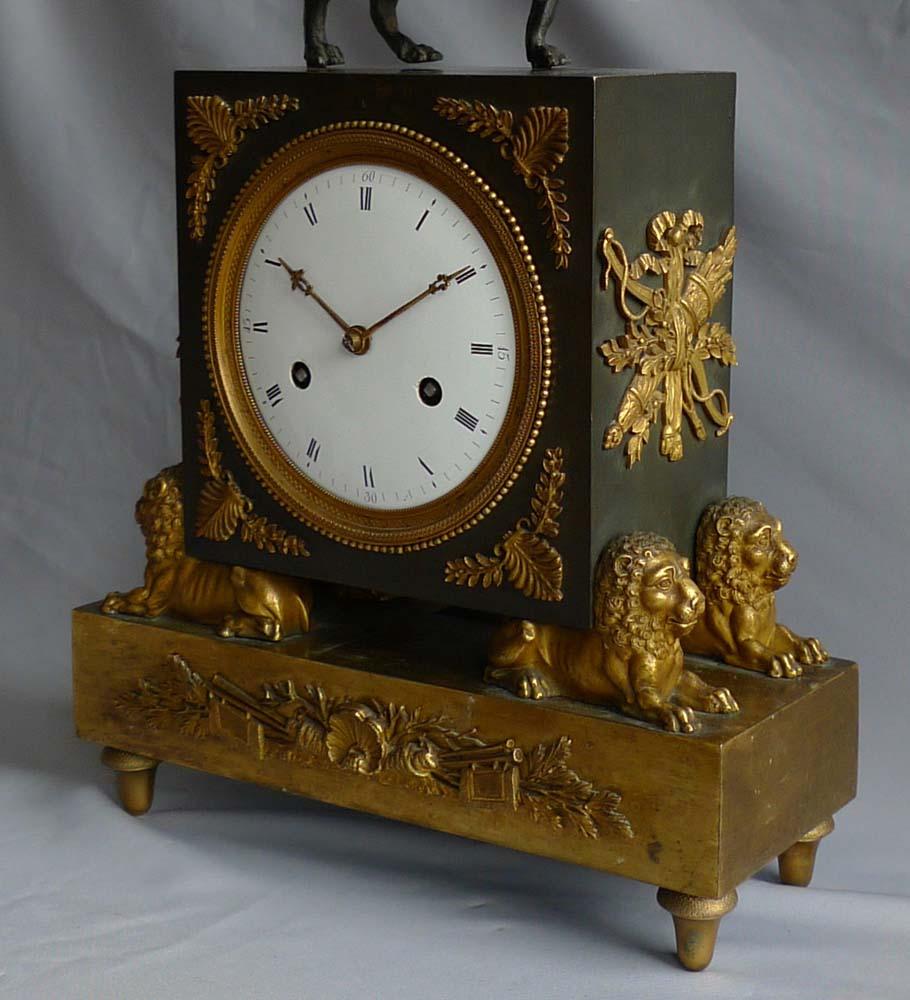 Magnificent and very rare French Directoire or Empire clock in patinated bronze and the finest highly worked ormolu. Set upon toupee feet below a rectangular ormolu base with applied ormolu mount to front. Lying upon the base are four very well cast