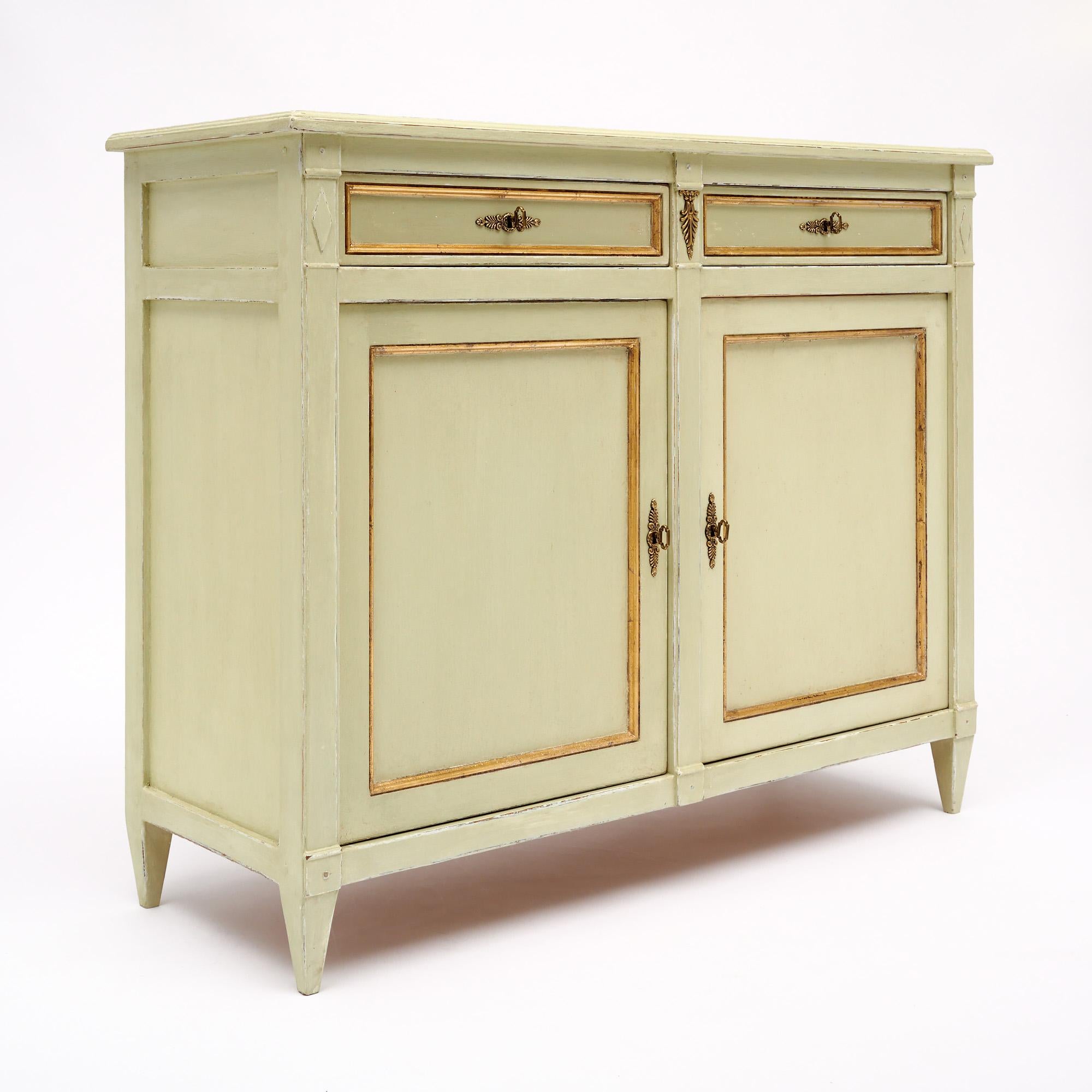 Buffet from France in the Directoire style. This piece is made of solid wood construction that has been finished with a milk paint in the pistachio green color. There is gold leaf trim and brass detailing throughout. There are two dovetailed drawers