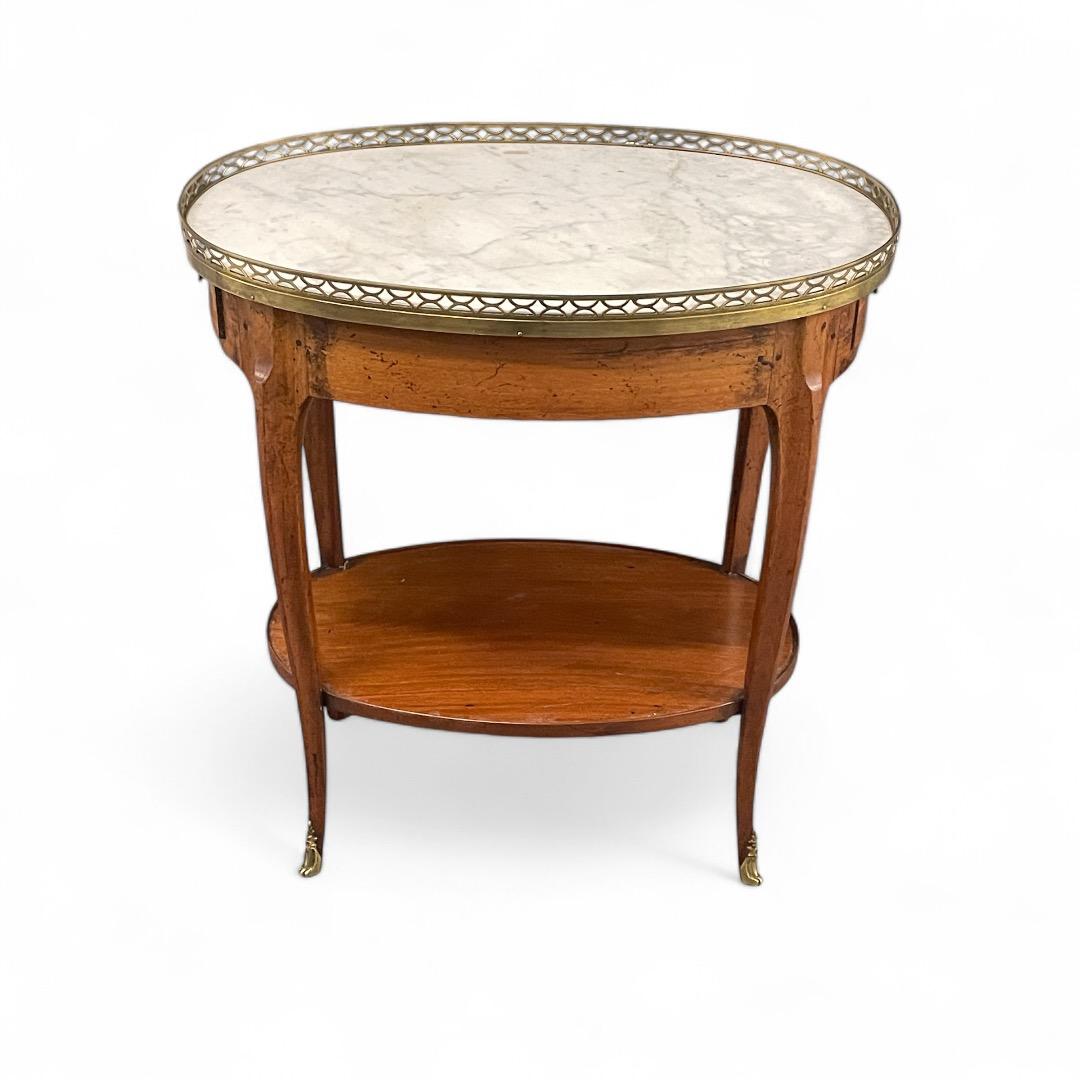 Dieser elegante, ovale Beistelltisch aus der Zeit des Directoire um 1800 ist aus massivem Nussbaumholz gefertigt und verfügt über eine schöne Marmorplatte mit einer Messingreling. Dieser antike französische Beistelltisch ist in gutem Originalzustand