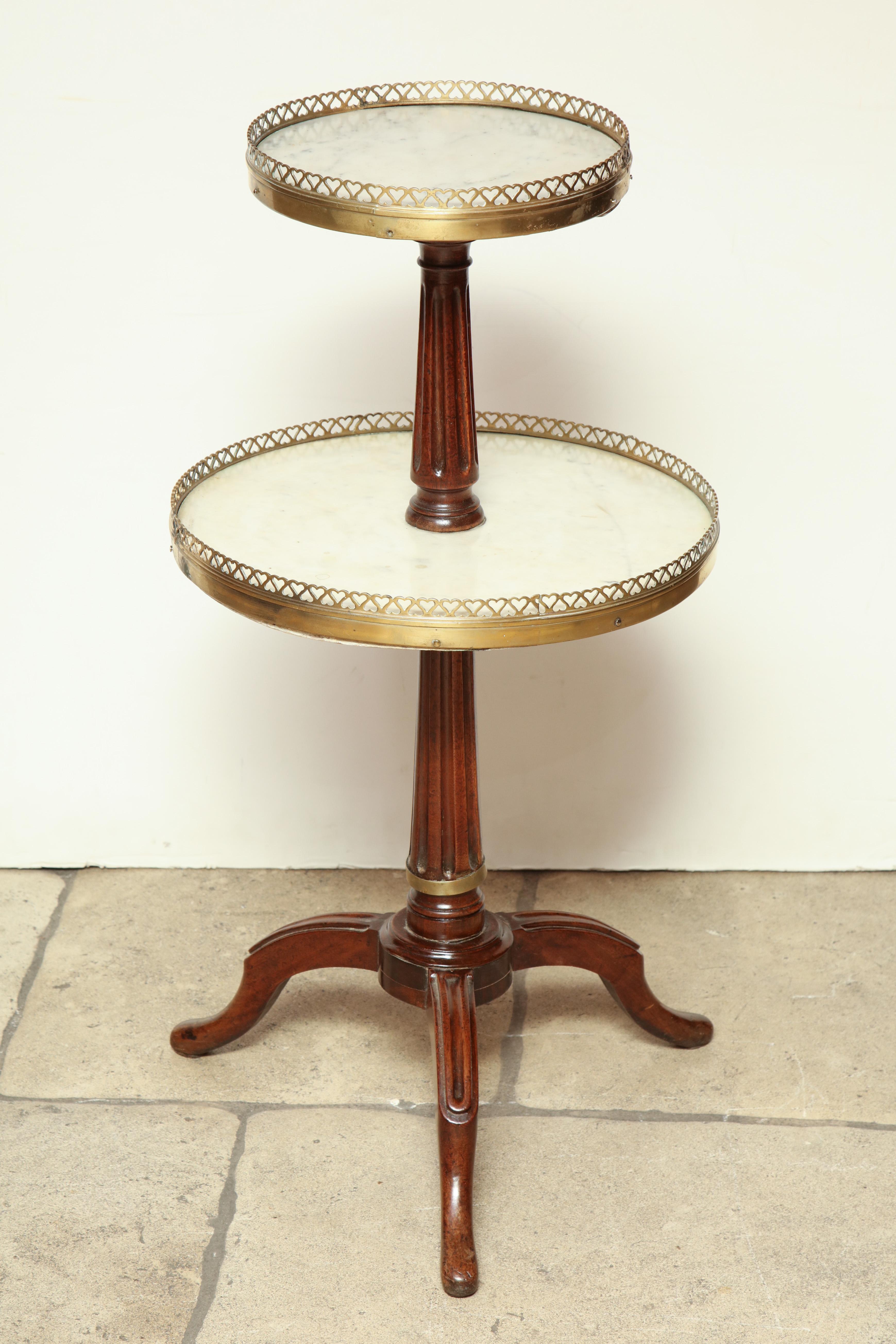 A sweet little French Directoire mahogany two-tier pastry table with marble tops, pierced bronze galleries, a turned and fluted column support with three outflaring legs.