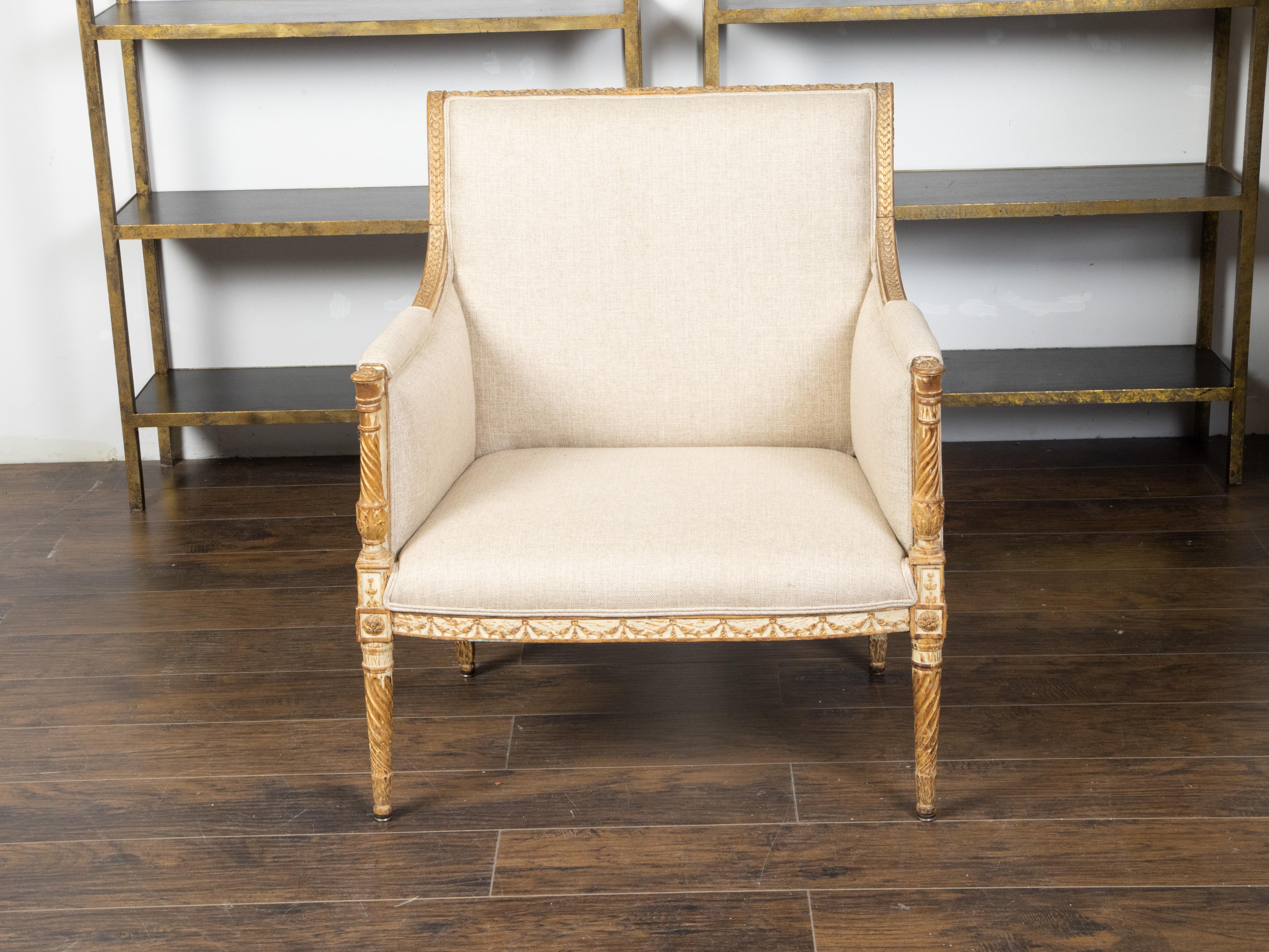 A French Directoire style painted and gilt wood bergère chair from the 19th century, with out-scrolling back, carved motifs and new upholstery. Created in France during the 19th century, this Directoire style bergère features a delicately