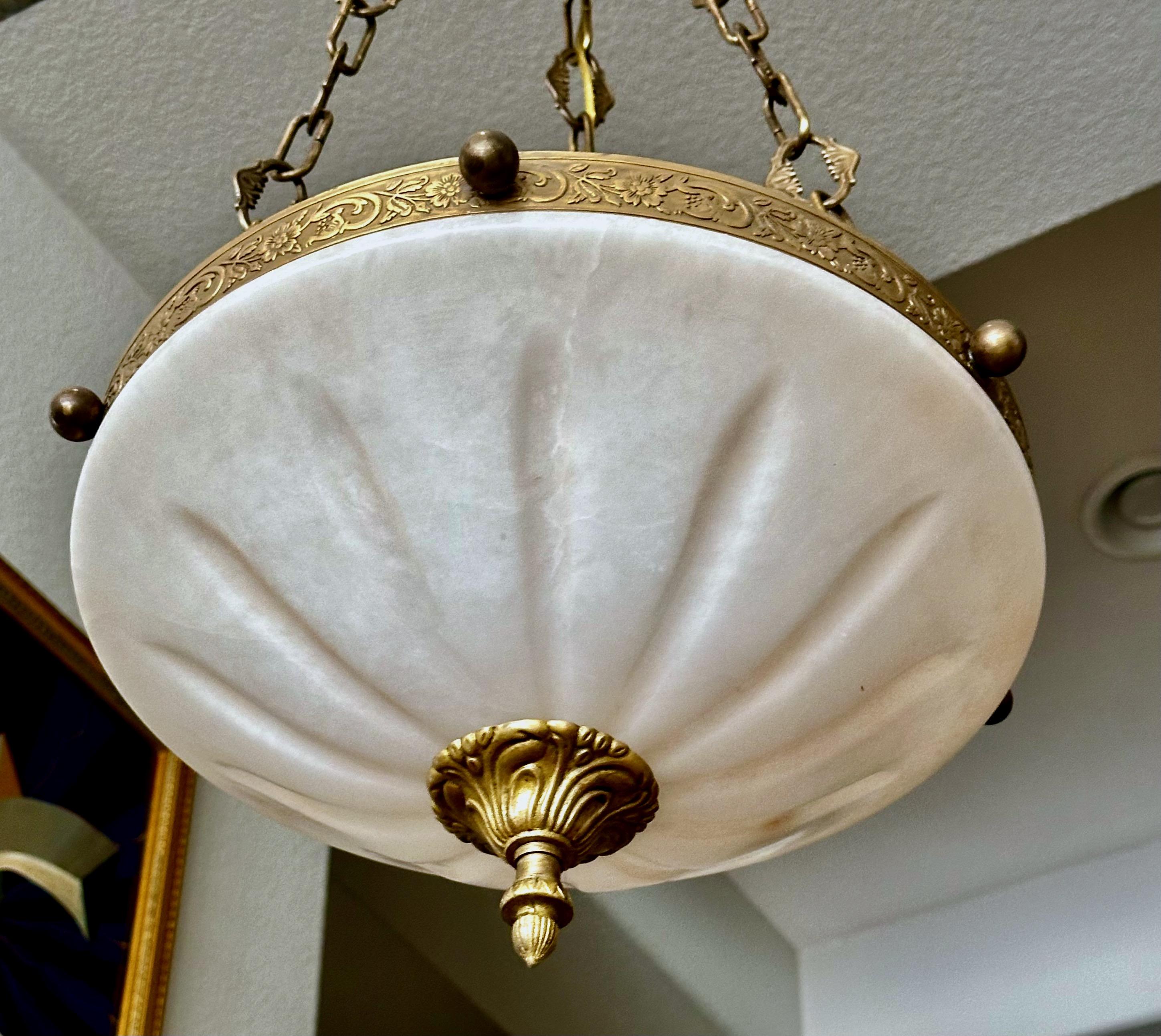 Alabaster pendant light or chandelier with aged patinated brass fittings in the Directoire style. Expertly carved with incised sunburst pattern design. Wired for US, fixture uses three candelabra size bulbs. 

Measures: Alabaster is 14