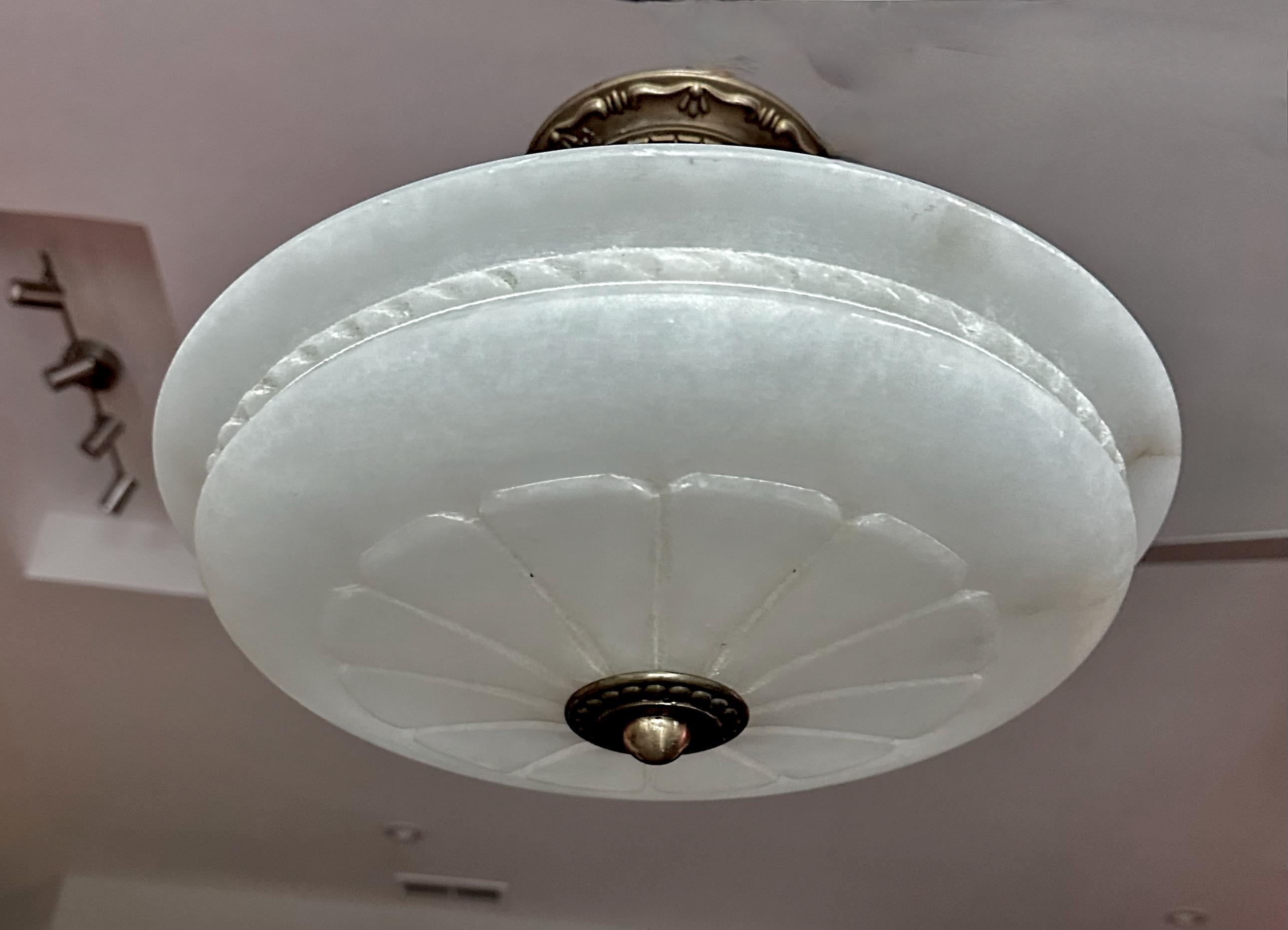Alabaster flush mount ceiling light with aged patinated brass fittings in the Directoire style. Nicely carved with starburst pattern. Wired for US, fixture uses 3 candelabra size bulbs. 

