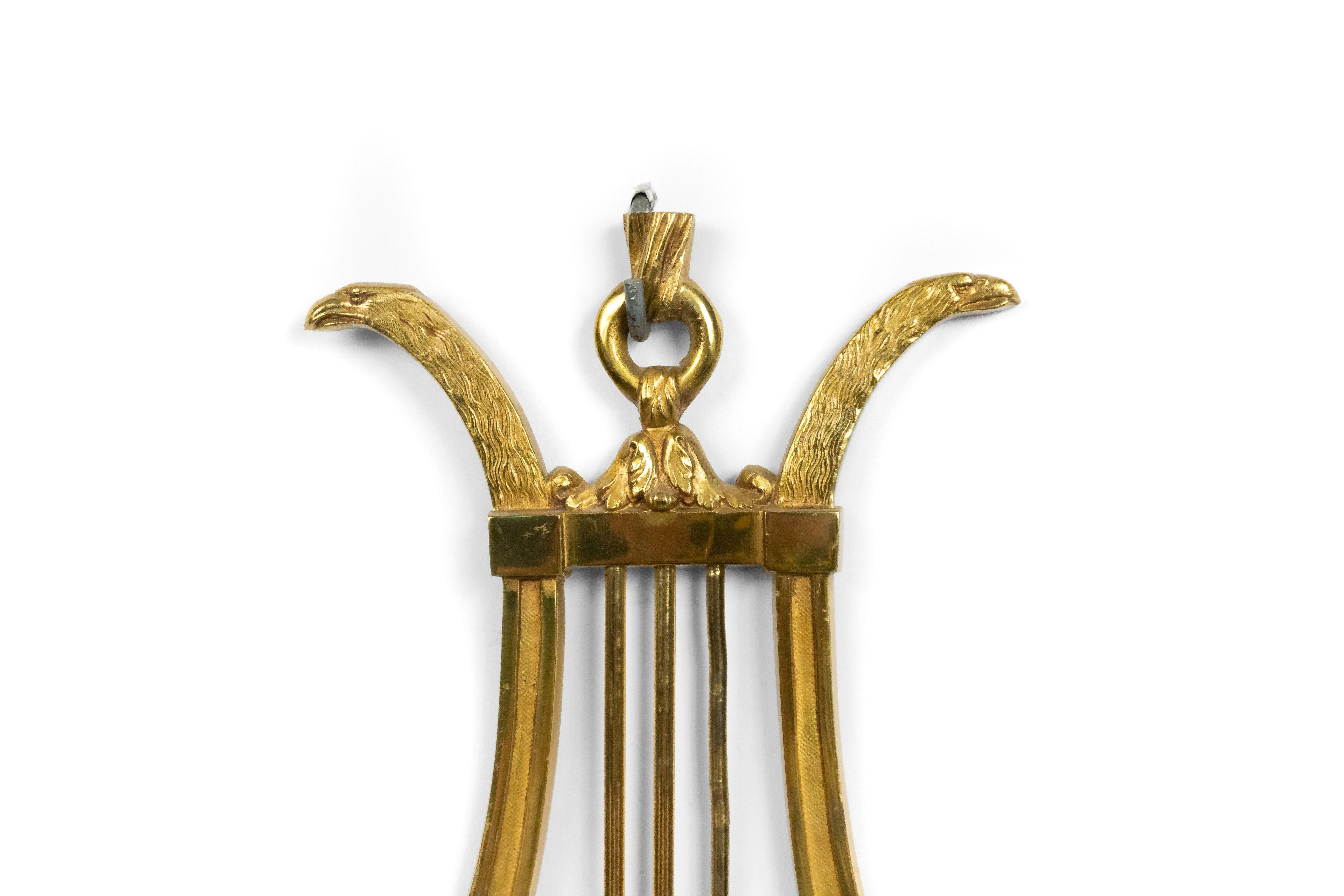 Pair of French Directoire style brass lyre design 3-arm wall sconces with 2 eagle heads, 20th century.