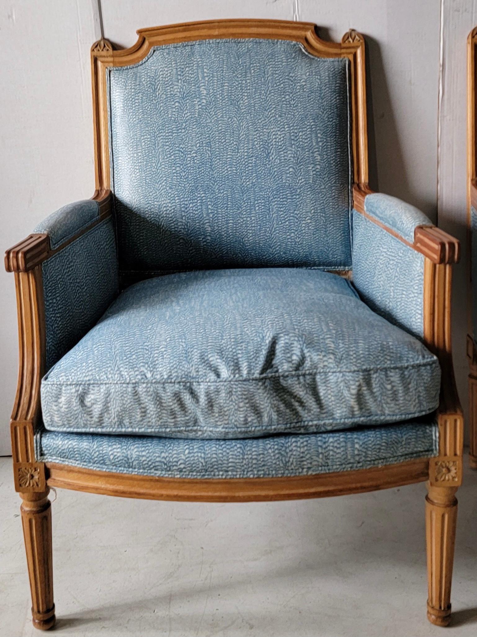 This is a pair of French directoire style club chairs in a vintage blue and white chintz. The frame is a cerused oak, and the cushions are down. Upholstery shows wear with no holes.