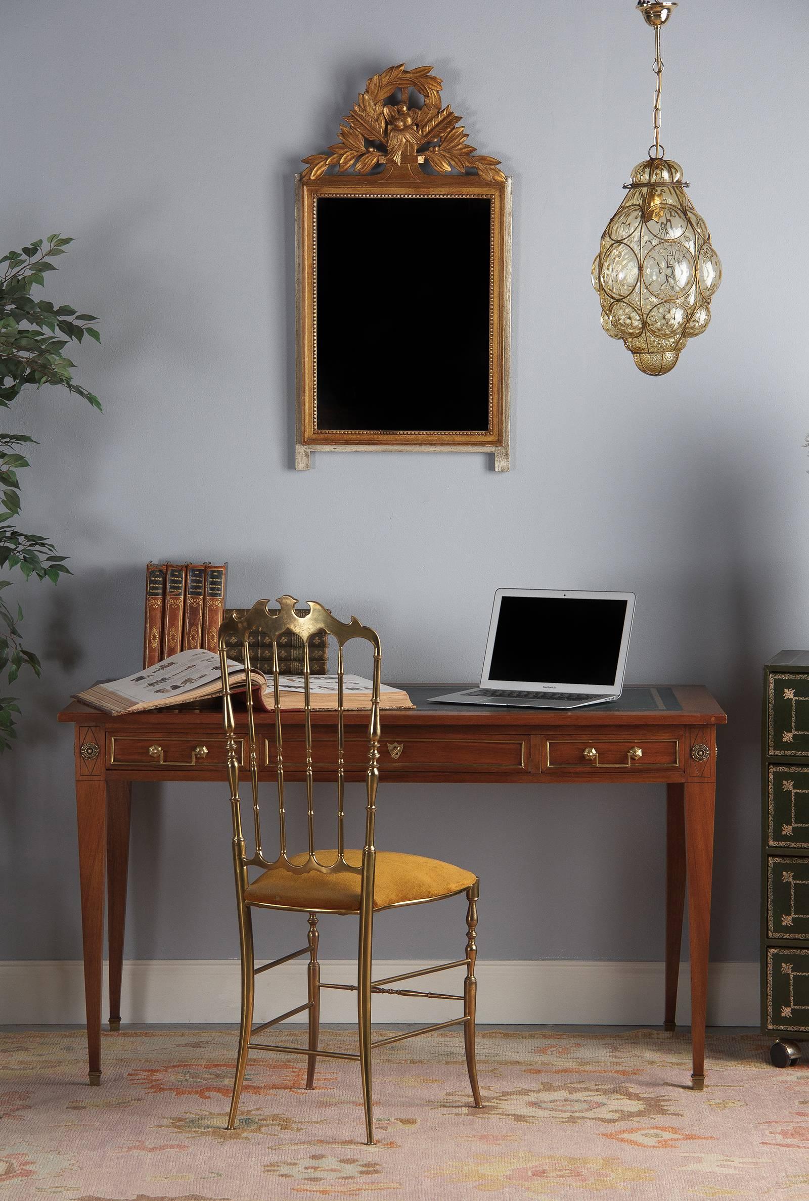 A stately Directoire style cherrywood desk with green leather top, French, circa 1900. Cherrywood construction with brass hardware and embellishments, embossed and gilt green leather top. Clean lines throughout with straight, tapered legs, incised