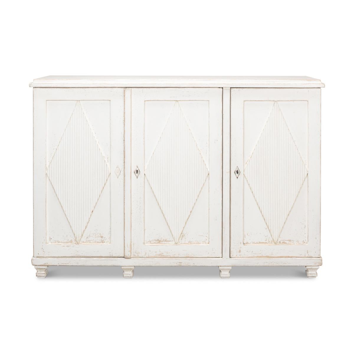 French Directoire Style credenza in an antiqued white distressed painted finish, with diamond reeded patterns, a fitted interior with shelves and three drawers, diamond escutcheons and raised short tapered legs.

Dimensions: 66