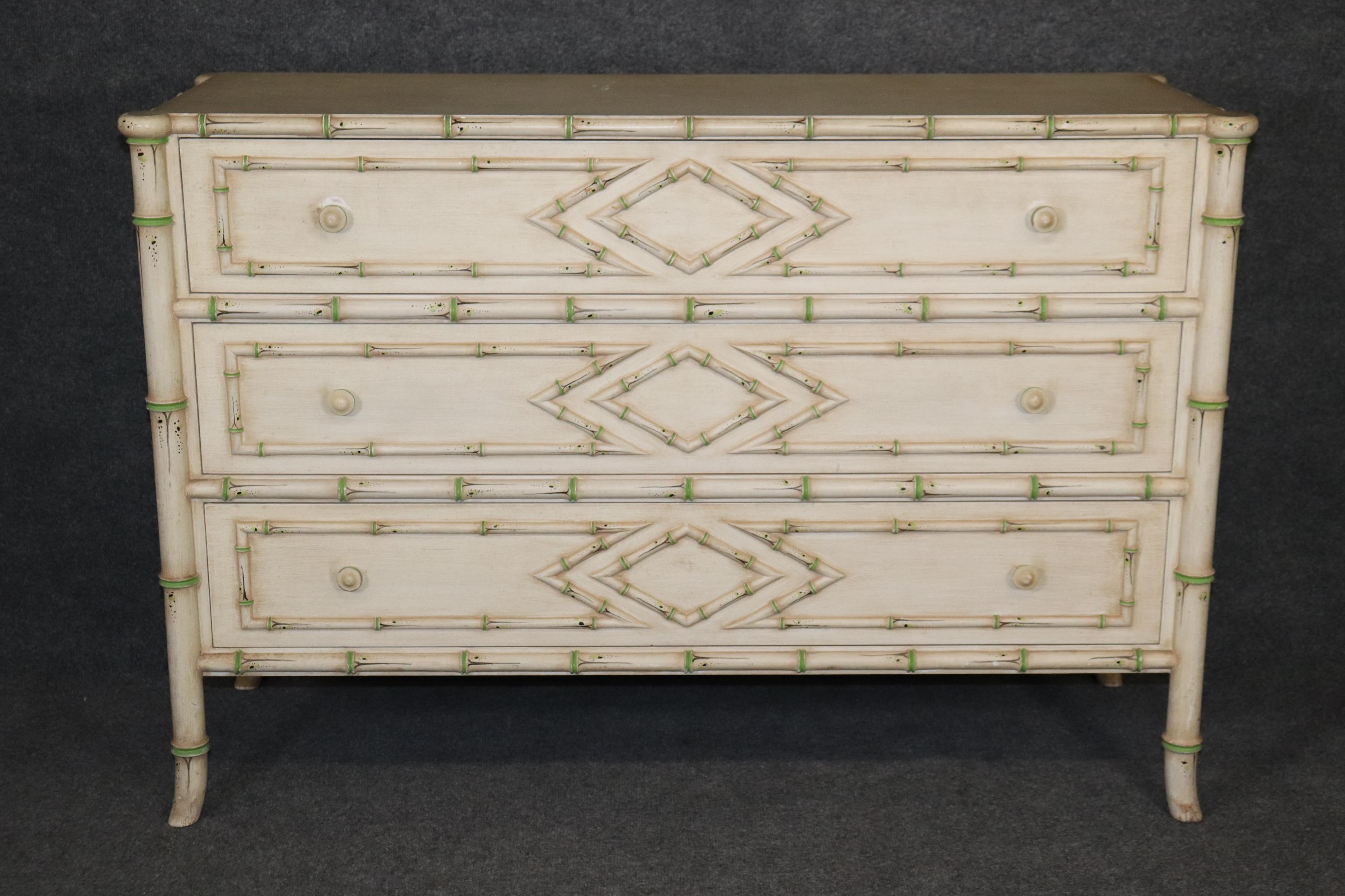 This is a gorgeous faux bamboo Directoire style French designed commode or dresser. The piece is painted in an antique white finish with light green accents and measures 47.5 wide x 17.25 deep x 32.25 tall and dates to the 1950s era.