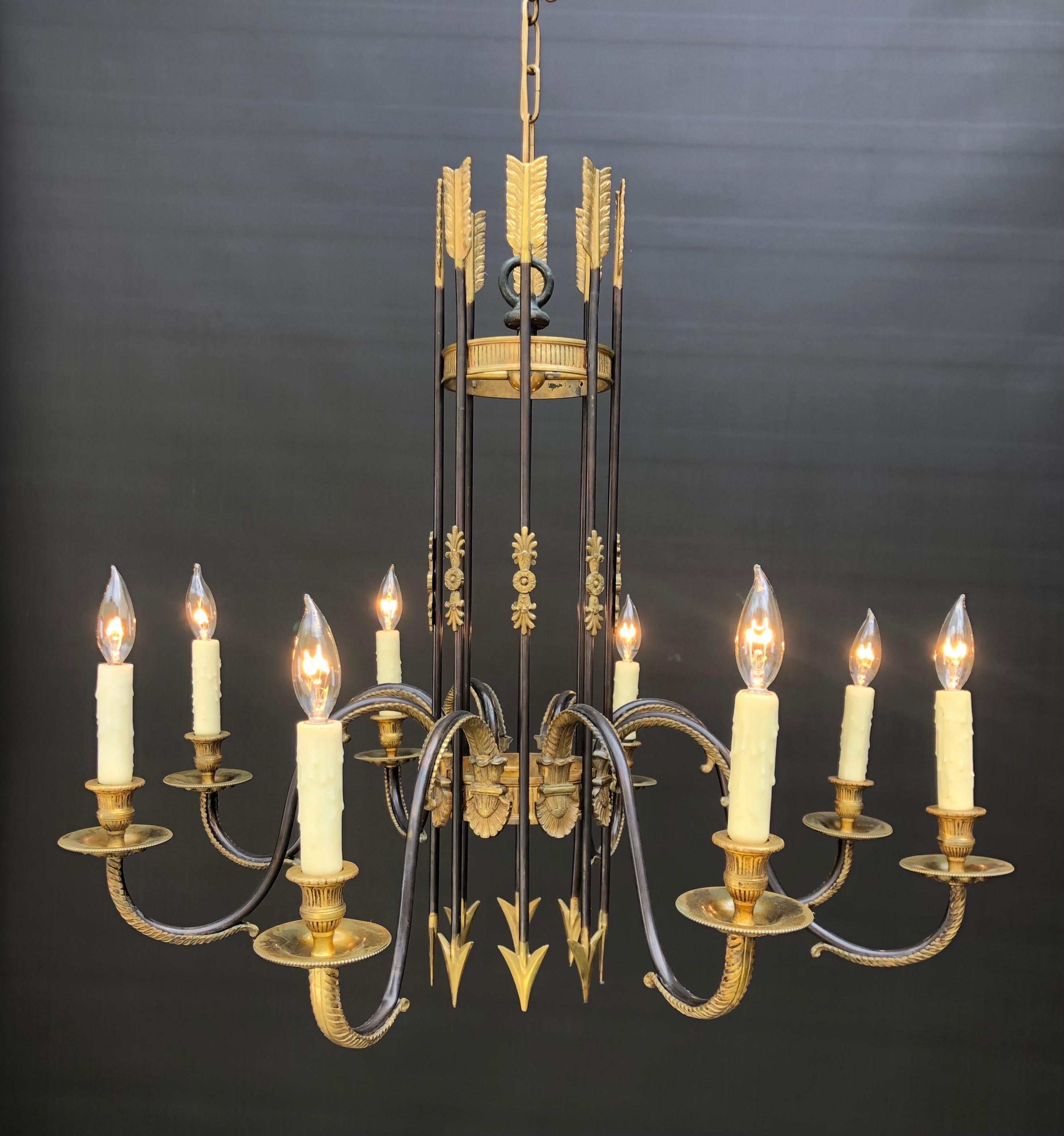 Il lampadario Regal Directoire è stato realizzato in Francia all'inizio del XX secolo. Il lampadario classico in bronzo ha una gabbia a cilindro a lavorazione aperta composta da otto frecce bicolore con alberi patinati, montate con lamelle dorate e