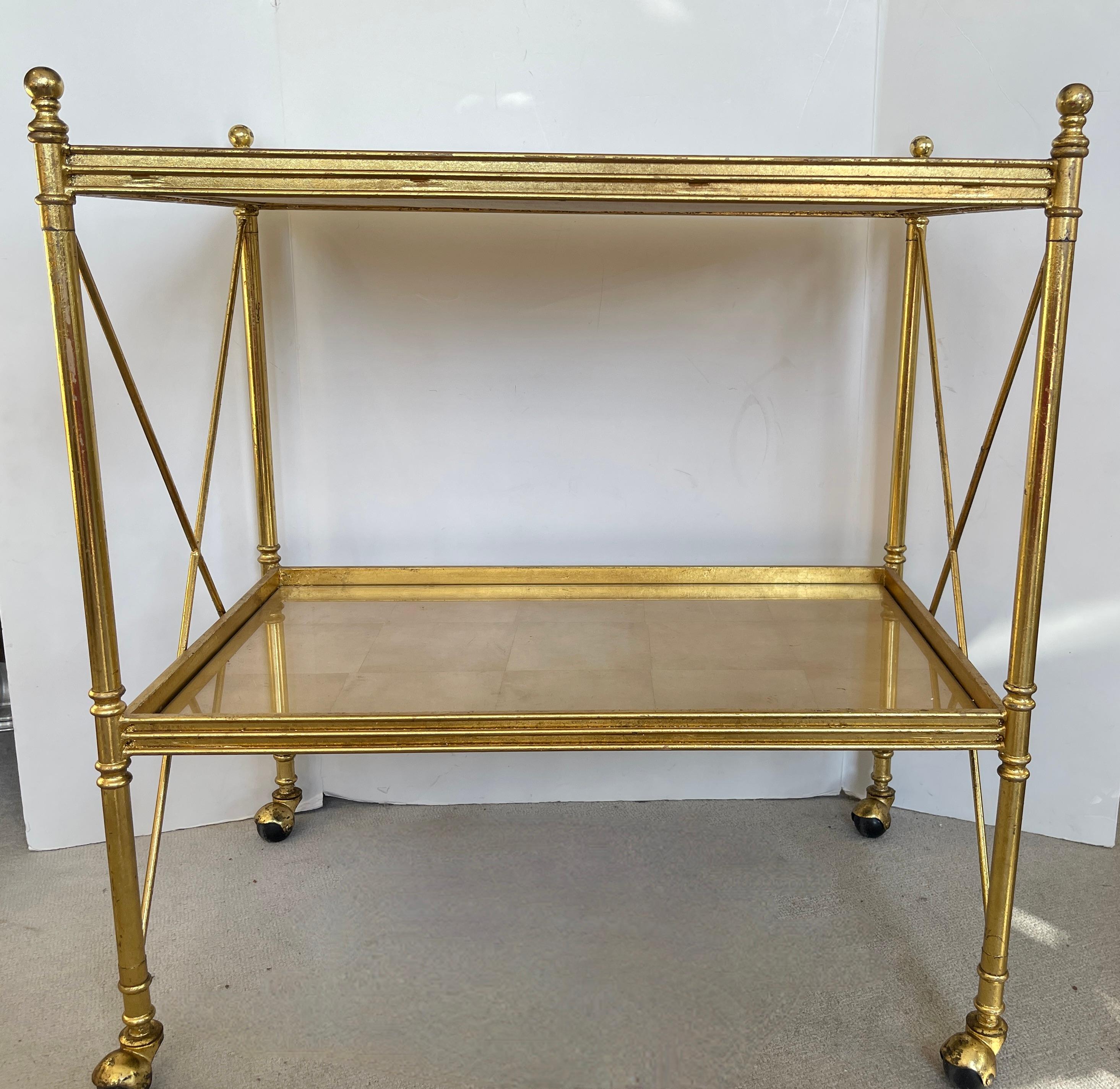 Just arrived , this striking  French Directoire Style Gold Leaf  under Glass Two Tier Tea Cart on Wheels.
The entire table is gold leafed,  the frame and the two shelves are Gold Leaf under glass.
The shelves are protected with glass.
There is some