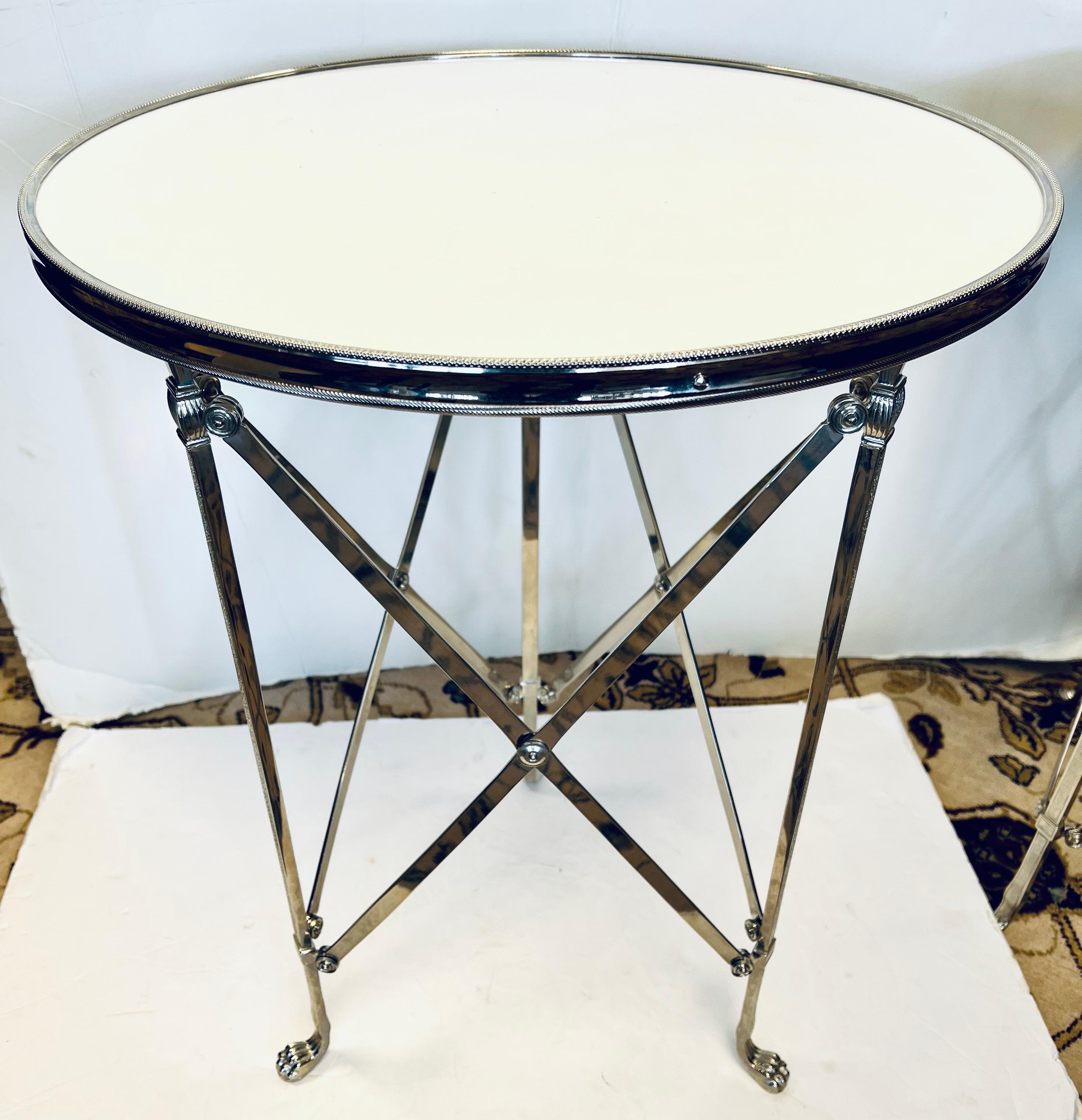 Pair of French style gueridon round side tables with inset white marble tops on chrome x-bases terminating in lion law feet.