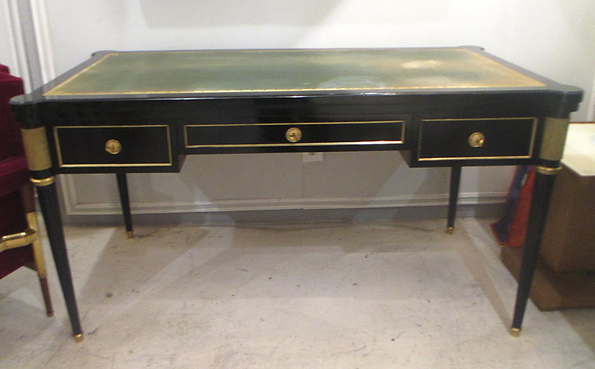 An over-sized Louis XVI-style leather-top writing desk on tapered legs ending in brass sabots.