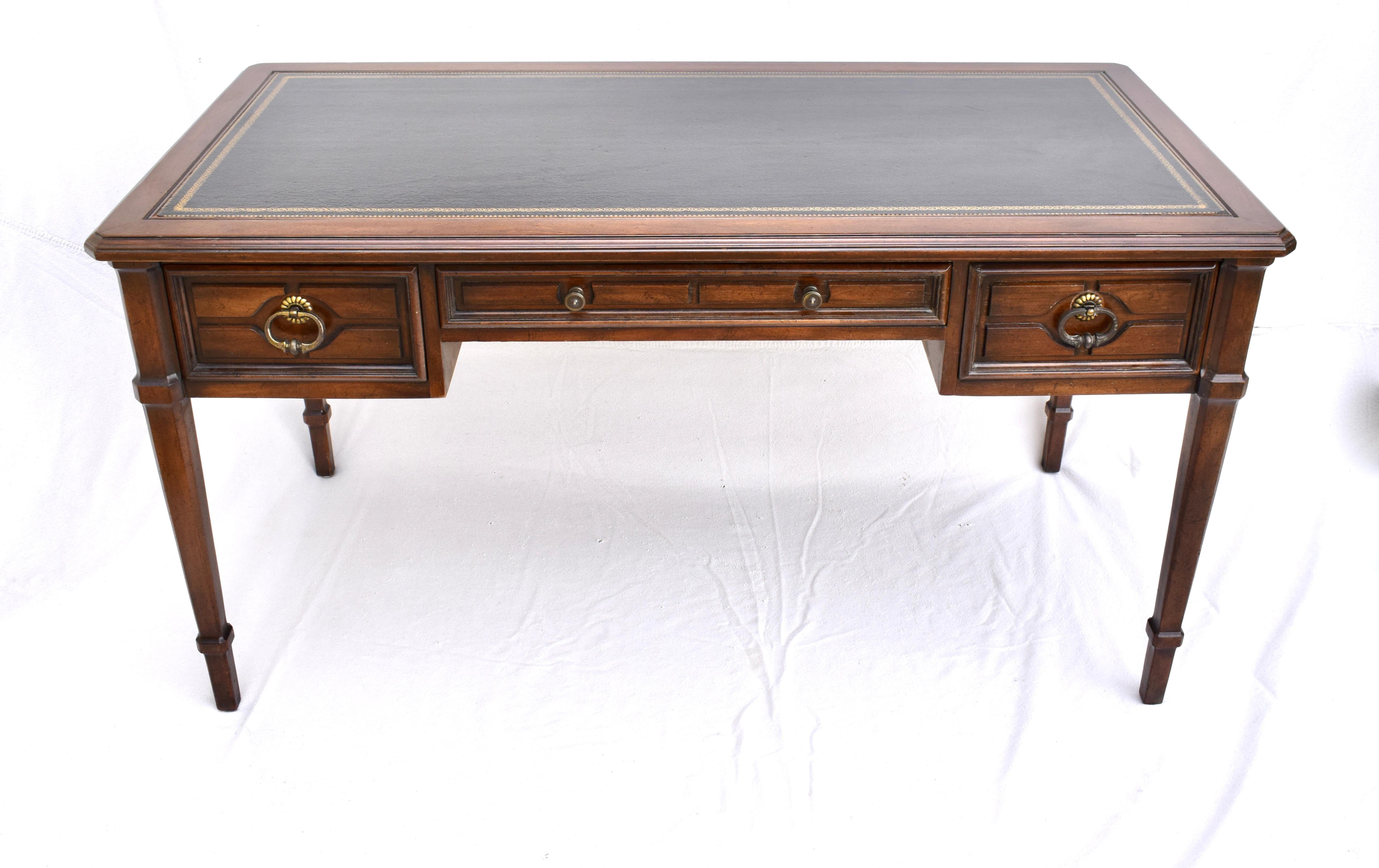 Striking French Directoire style walnut desk by Sligh Lowrey with three dovetailed drawers finished on all sides with striking black gold tooled leather top. Classic lines suitable for open floor plan placement.