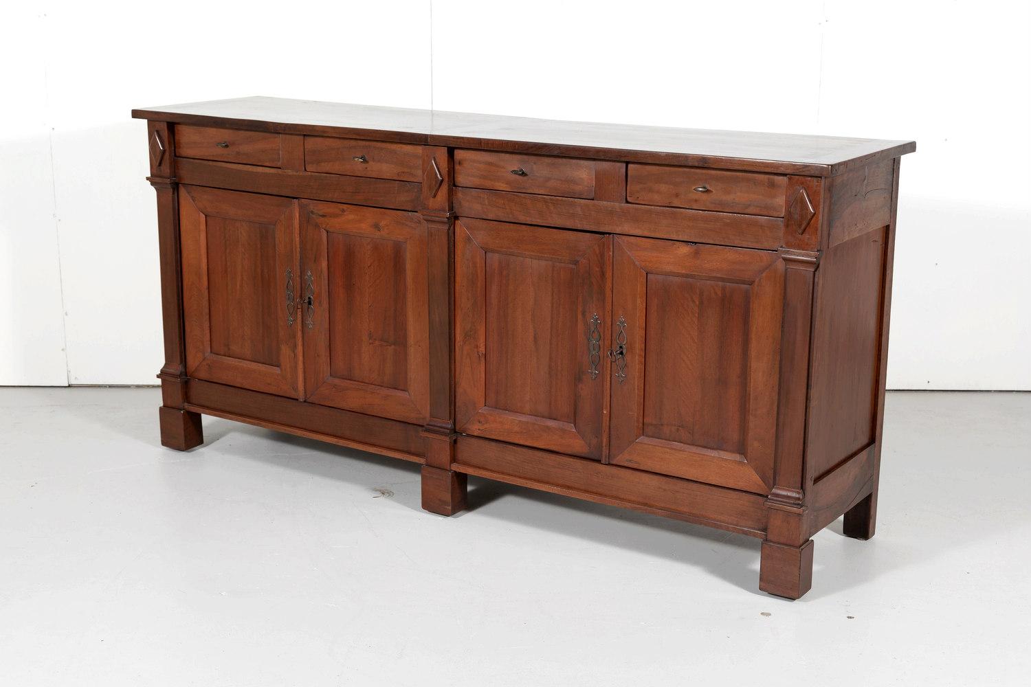Handsome French Directoire style enfilade handcrafted from sold walnut by talented artisans near Lyon. Rectangular top above four drawers over four panel doors divided by pilasters having typical neoclassical carved diamond motifs. Doors open to
