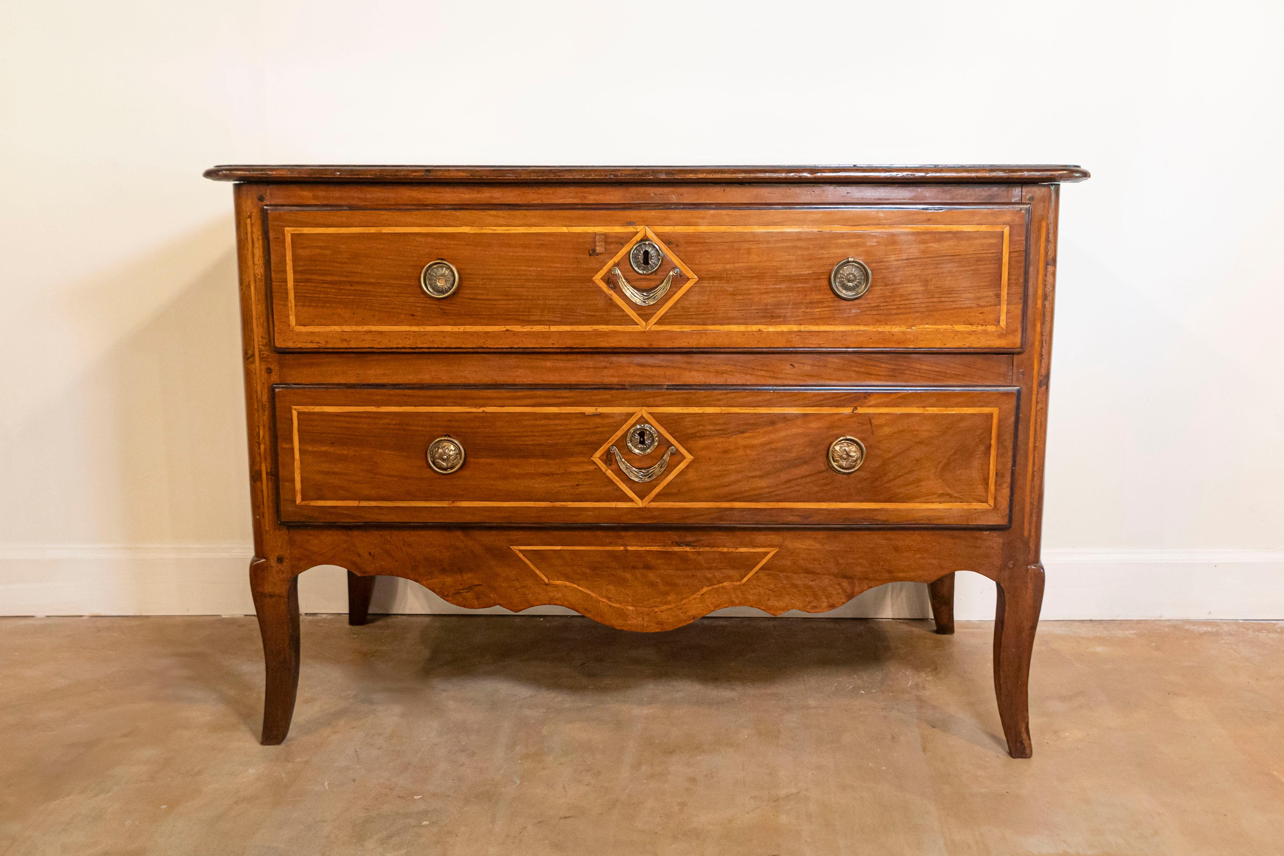 A French Provençale Directoire period two-drawer commode with banded inlay from the late 18th century. This French two-drawer commode was born in the mid-1790s, in the Provence region of Southern France. Featuring a rectangular top with rounded