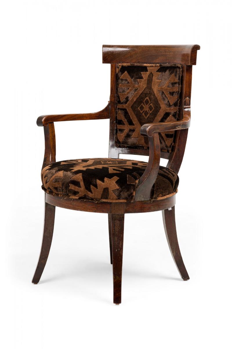 French Directoire (early 19th Century) walnut armchair upholstered in a raised textured brown and black geometric fabric, with curved bar toprail and oval seat on carved sabre legs.

Condition: Good; Wear consistent with age and use