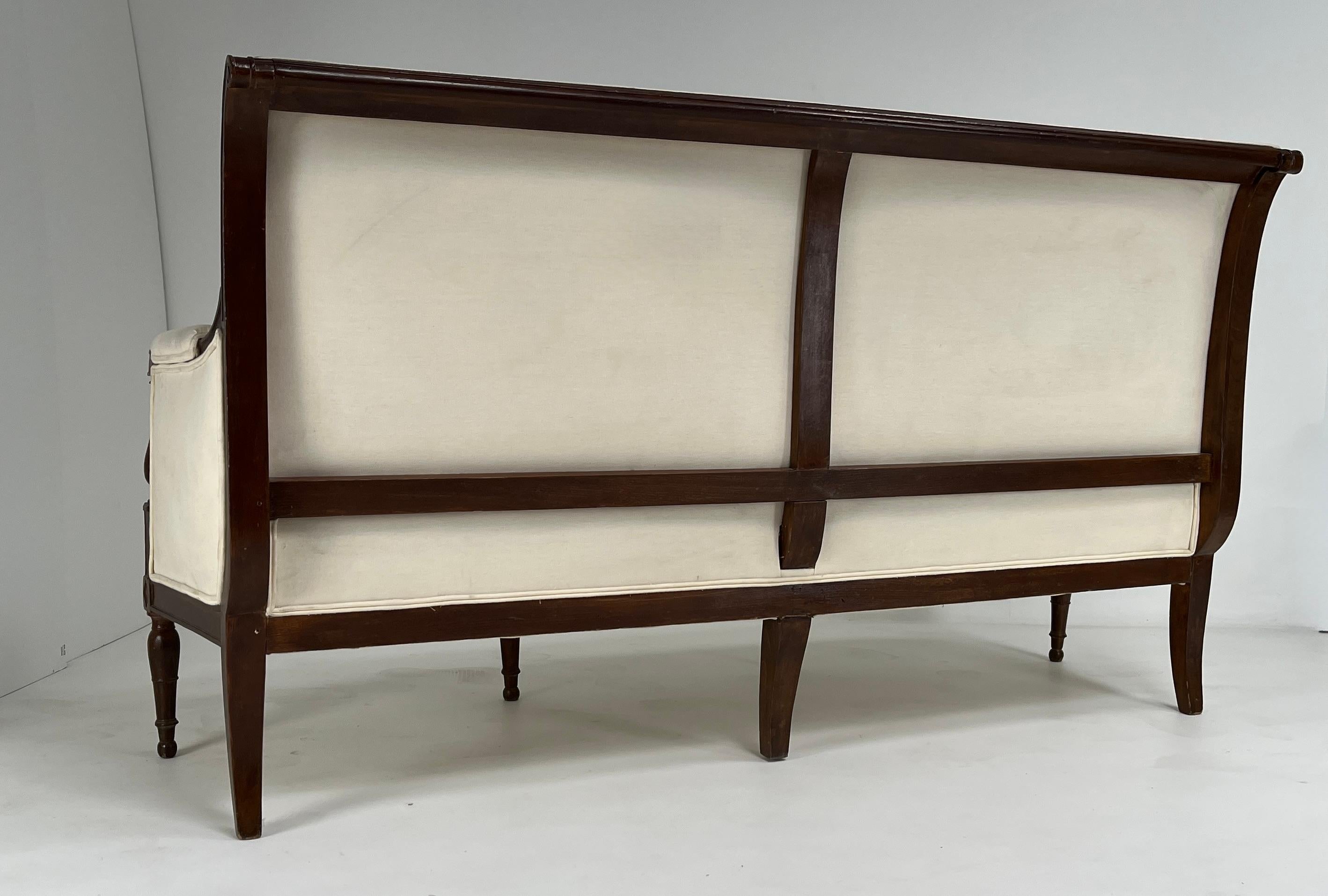 Un maestoso divano in stile Direttorio francese, realizzato in noce massiccio e caratterizzato da un'eleganza senza tempo e da linee architettoniche sobrie. Questo pezzo a tre posti riflette la sobria estetica neoclassica del periodo del Direttorio,