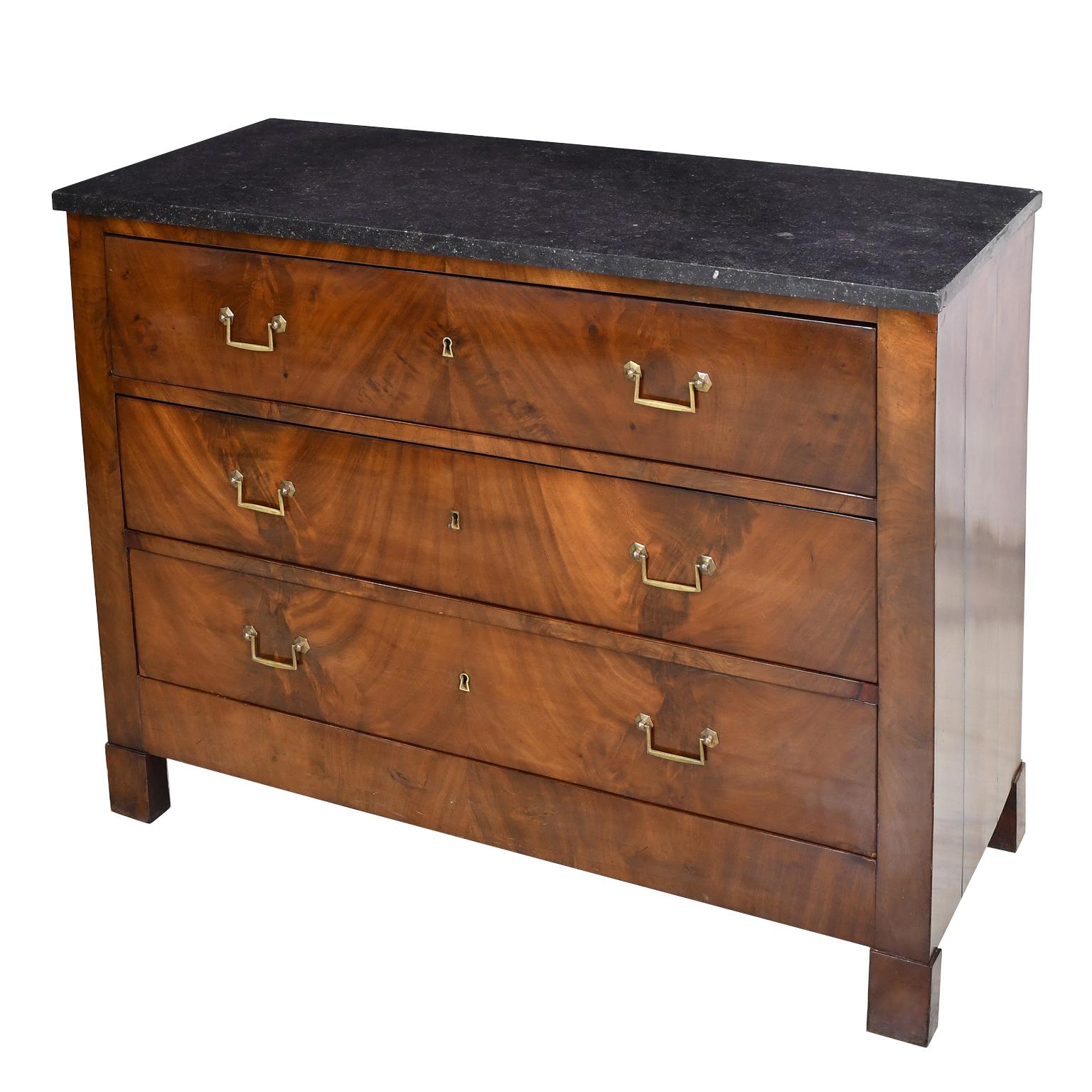 A handsome Directoire chest in West Indies mahogany with original black marble top, three drawers with original brass drop-bail pulls, and resting on square block feet. Features a beautiful bookmatched figured mahogany on the drawer fronts, France,