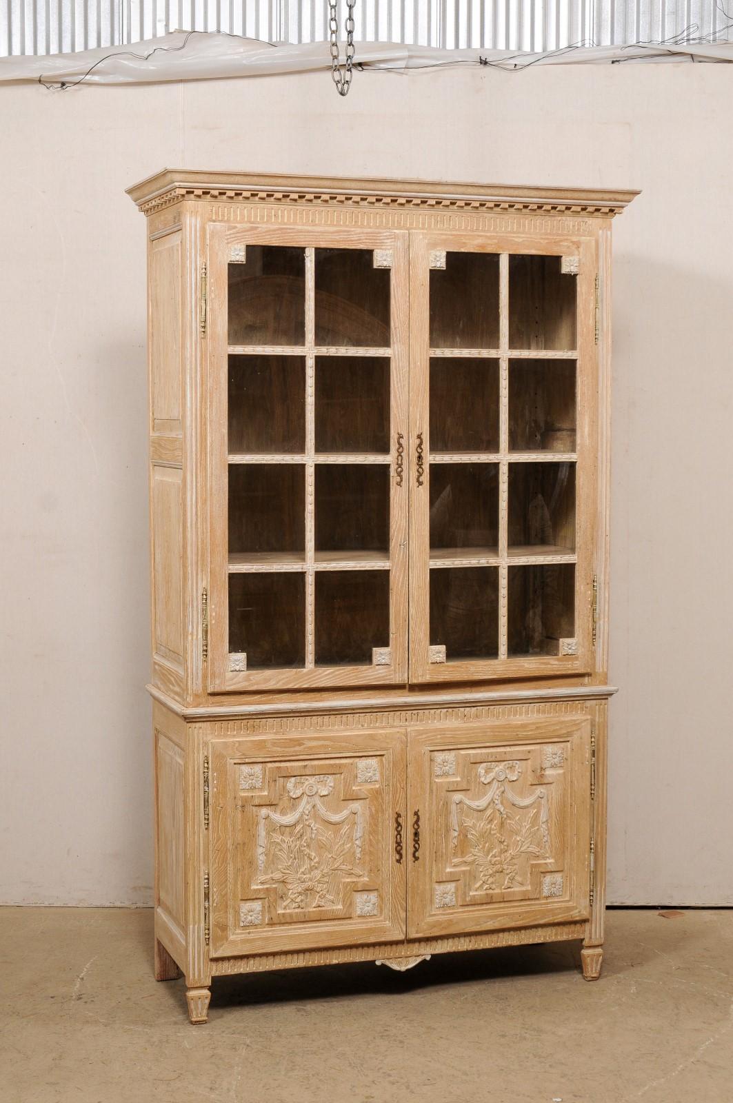 A French tall display and storage cabinet from the mid 20th century. This vintage cabinet from France, which stands approximately 7.5 ft tall, has been designed with a Neoclassical influence, which is apparent in the nice dentil molding found