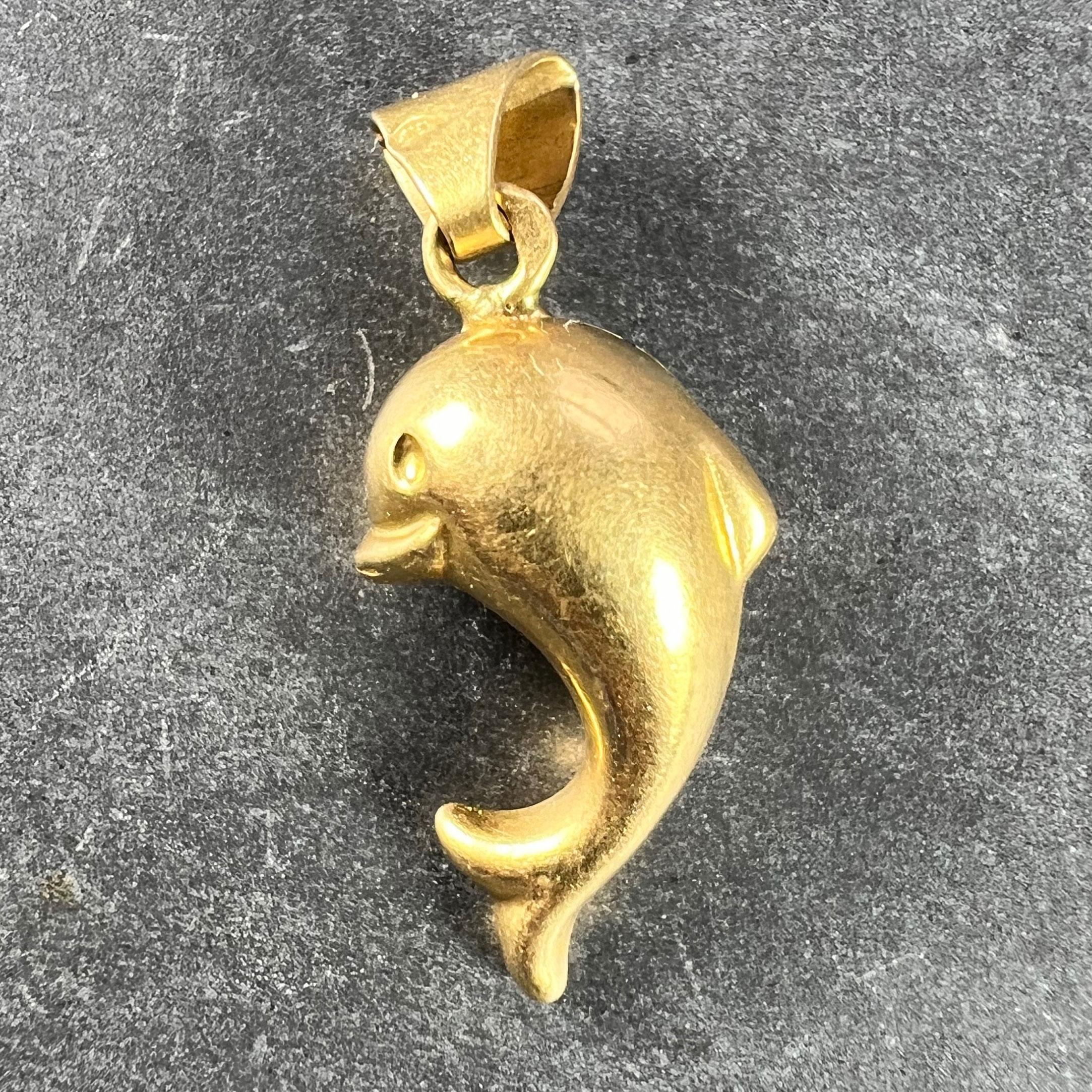 A French 18 karat (18K) yellow gold charm pendant designed as a leaping dolphin. Stamped with the eagle’s head for French manufacture and 18 karat gold.

Dimensions: 1.9 x 1 x 0.75 cm (not including jump ring)
Weight: 0.82 grams
(Chain not included.)