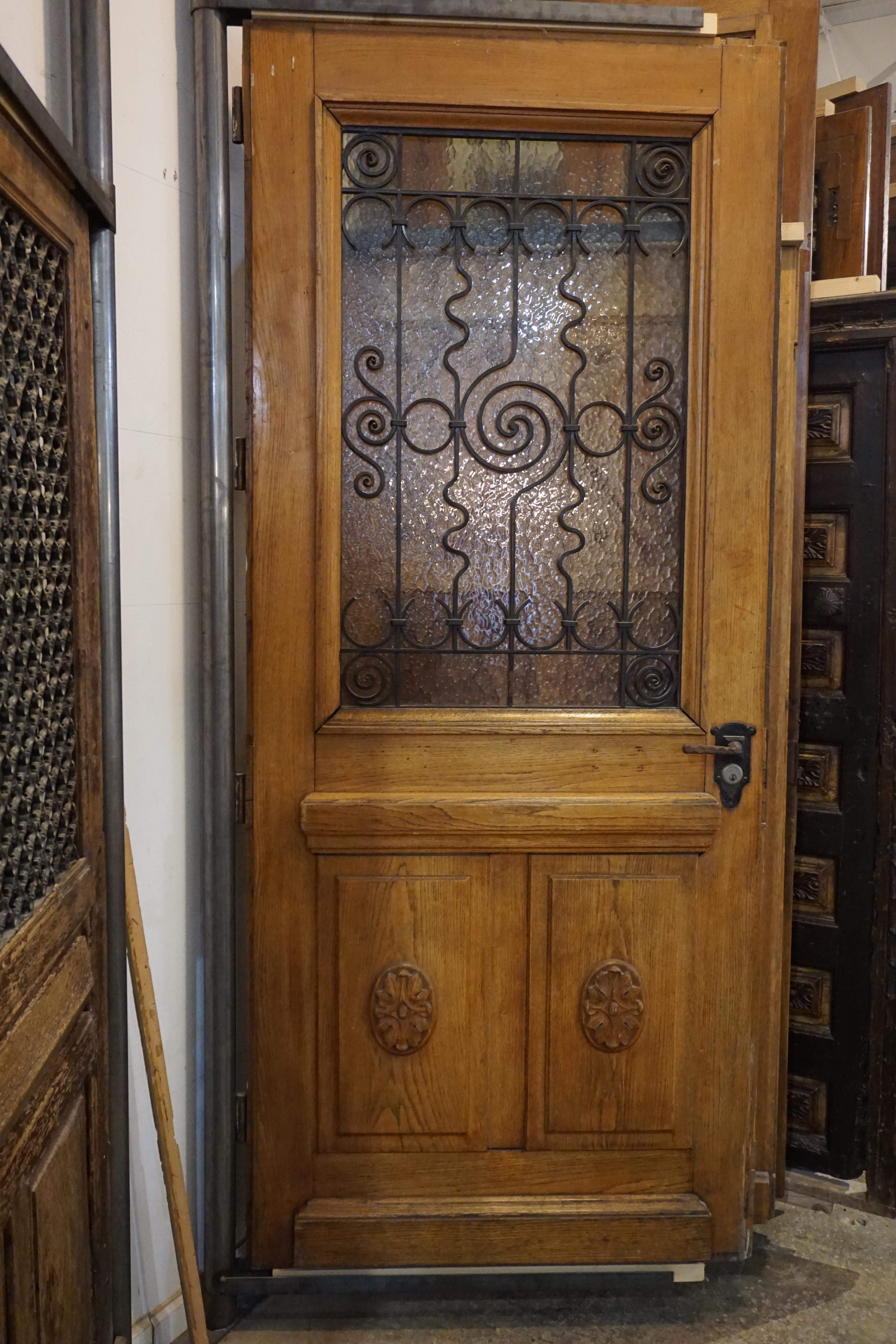 French oak entry door with ornate ironwork grille and lever handle. Applied rosettes to bottom panels.

Origin: France, circa 1890

Measurements: 41 1/4