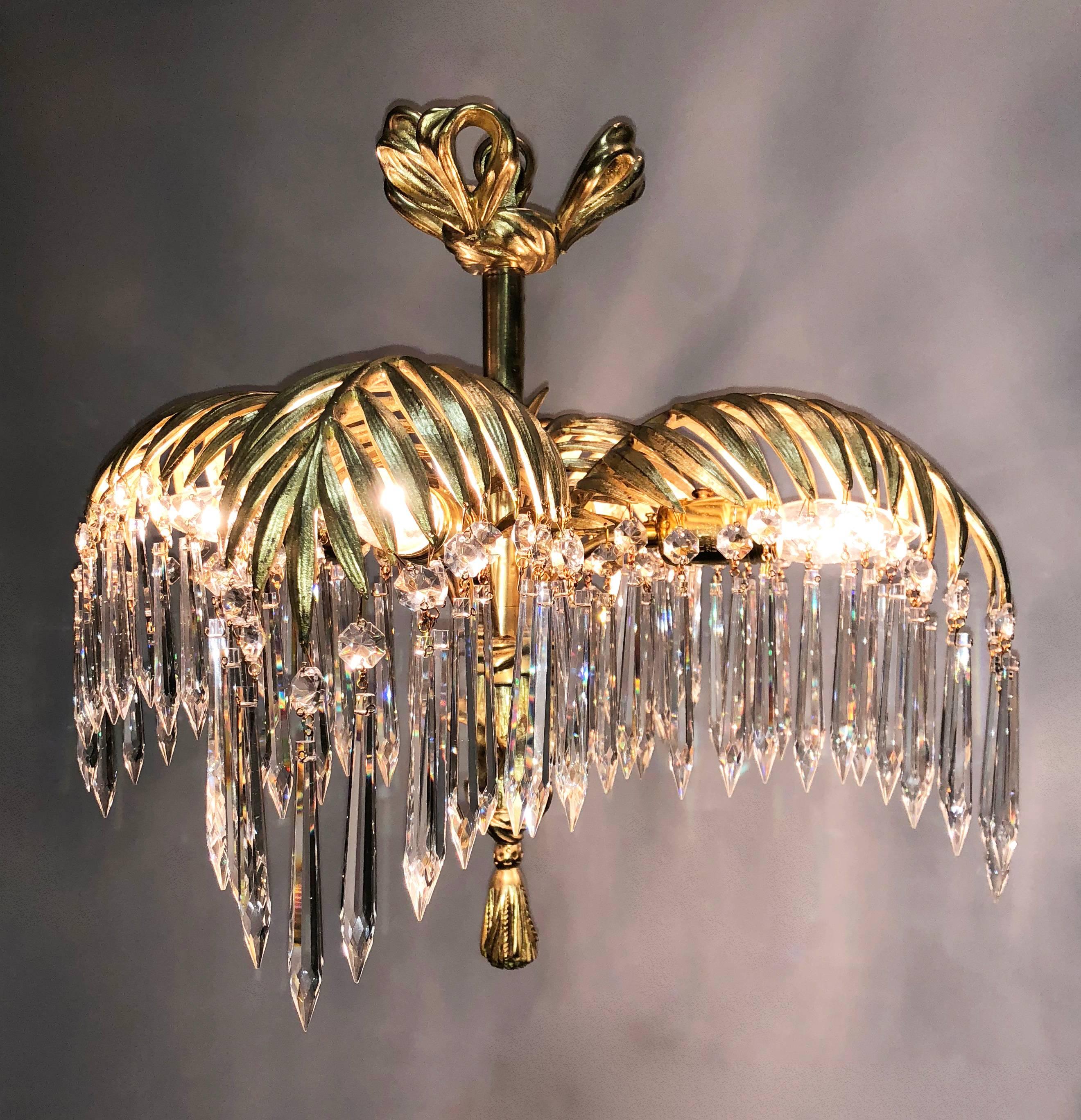 Dore Bronze palm fronds chandelier with ribbon canopy top with a faux tree center stem wrapped in ribbon coming down to a tassel. Hand-cut French crystal hand from the palm fronds. Edison bulbs are in the sockets. It is rare to find four palm frond