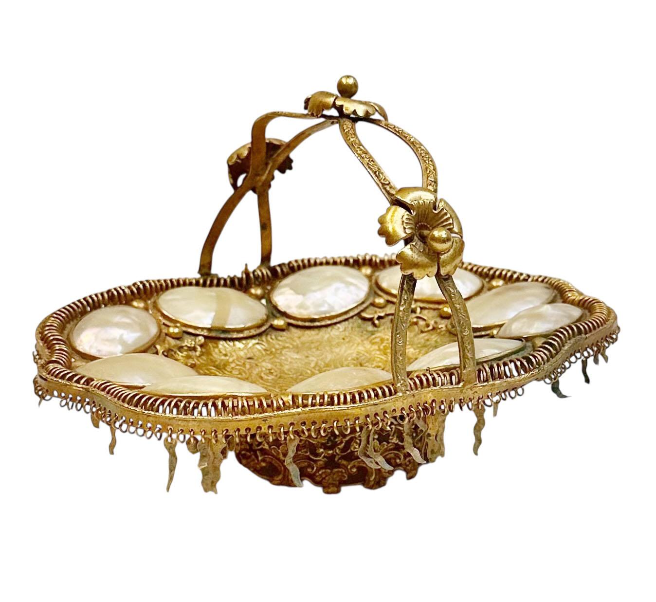 A rare and fantastical example of French decorative whimsy, circa 1890, this highly worked doré bronze basket is rich with symbolic and ornamental detail. The body features reticulated openwork, molded floral motifs, and applied mother of pearl