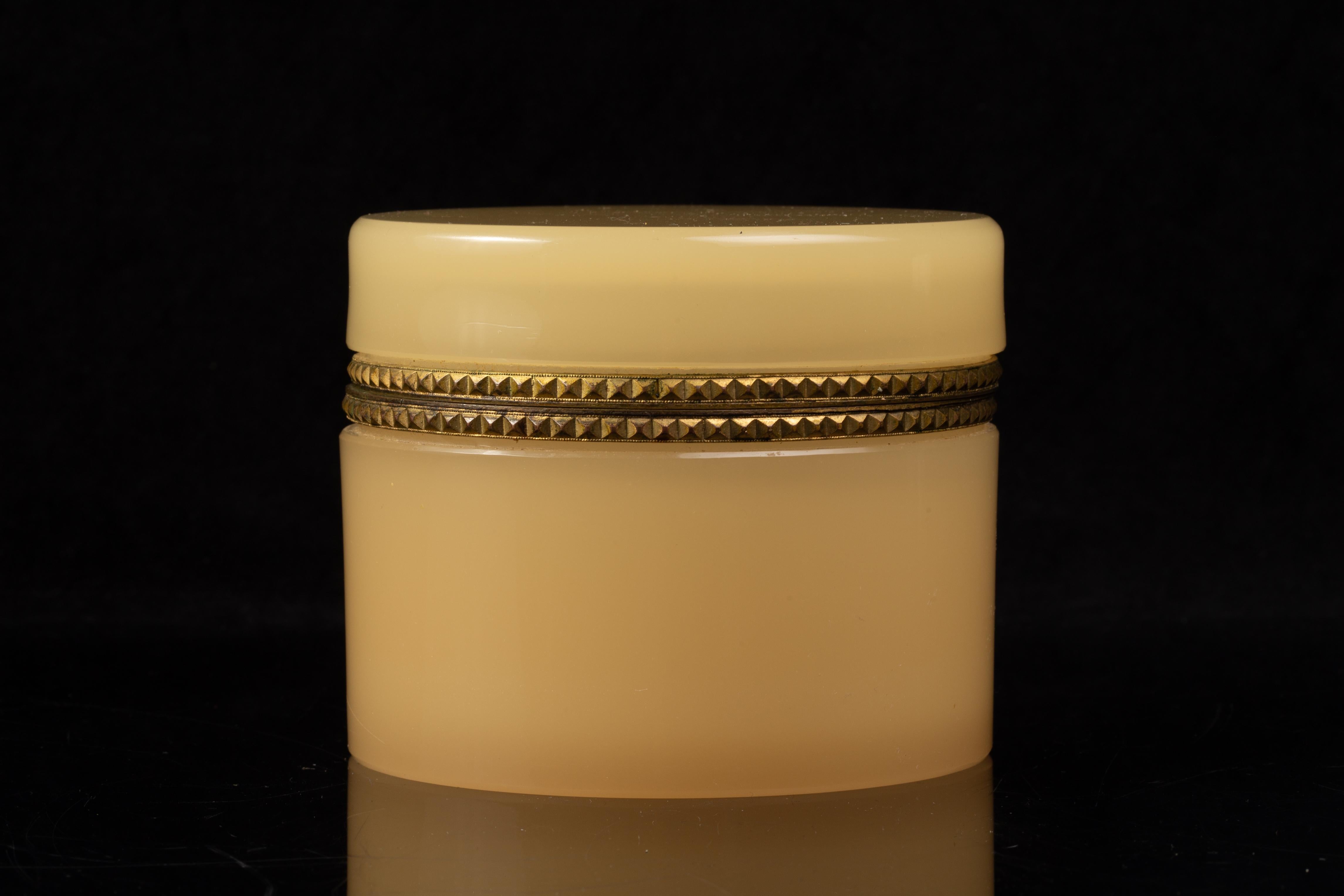 A French Dore Bronze Mounted Peach Opaline Crystal Round Form Covered Box.  The cylindrical form includes a flat-topped lid that fits precisely onto the base, joined by a decorative doré bronze mount. The mount is ornamented with a repeating