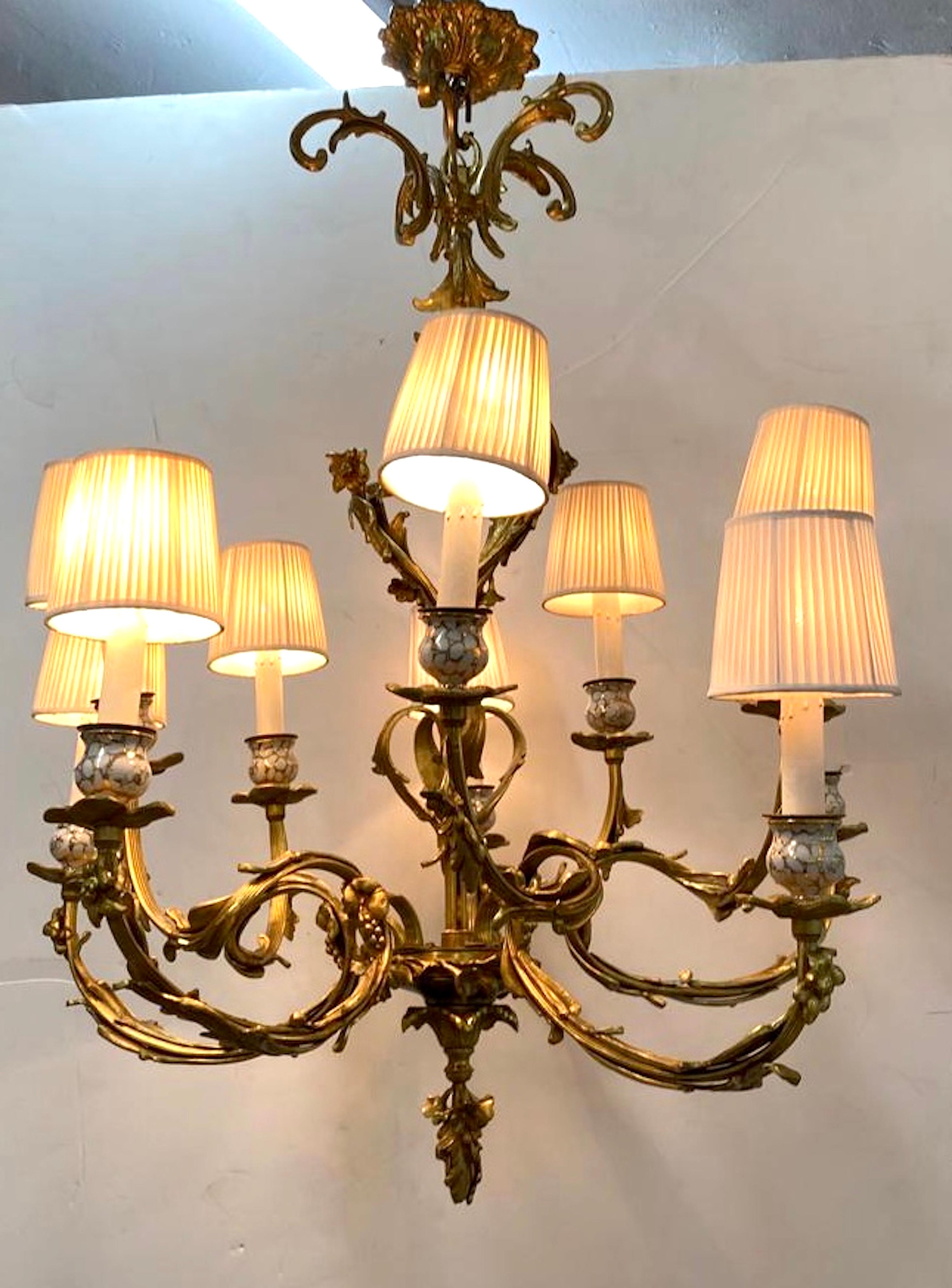 A very nice French dore' bronze chandelier in the Rococo style with ten lights. There are five sets of double arms. Each set has a higher and a lower arm ending with a dore' bronze bobeche and porcelain candle/socket holder. The chandelier features